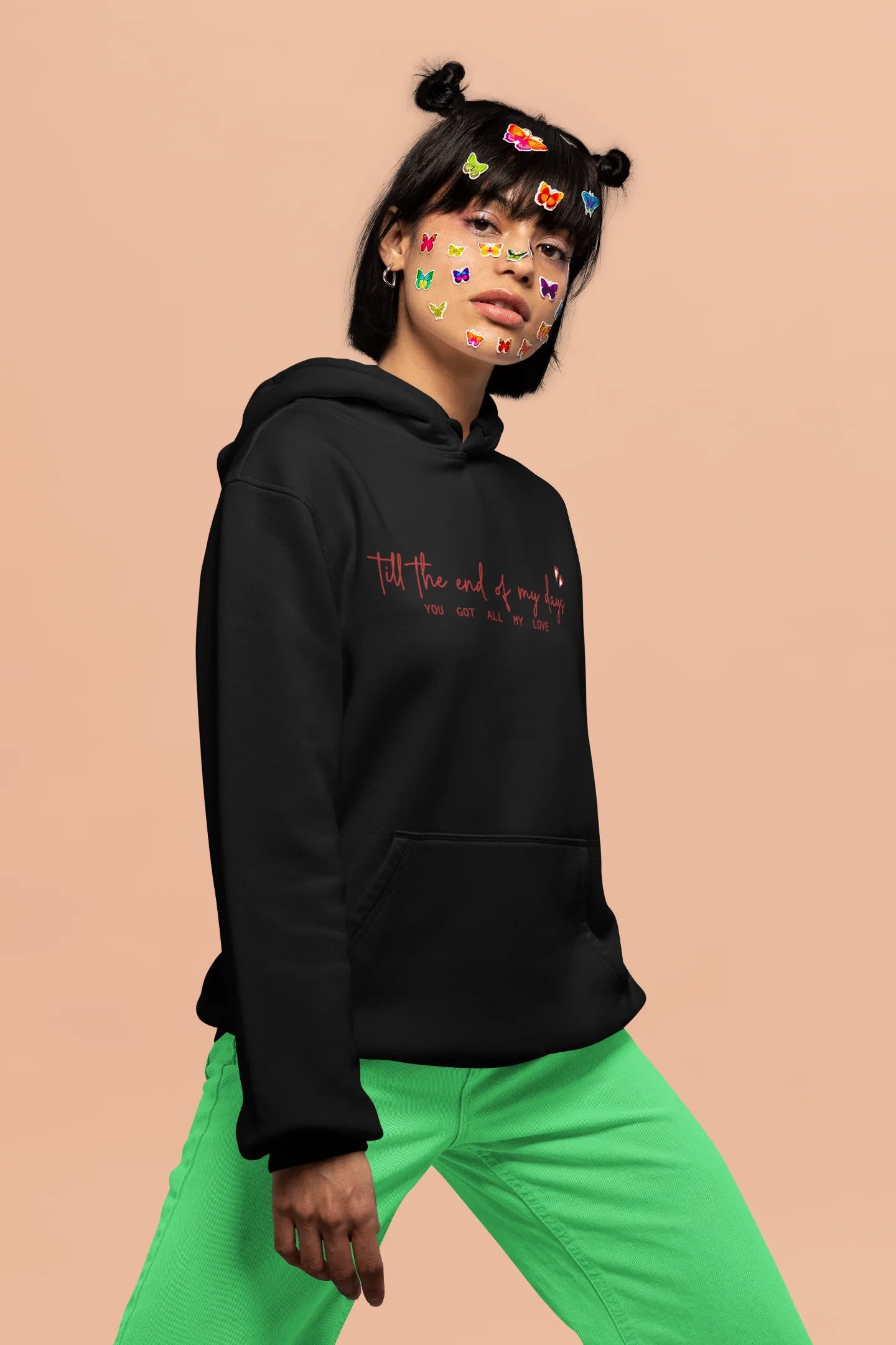 4th front view of a female model wearing a black hoodie with a heart design and the text "All My Love".