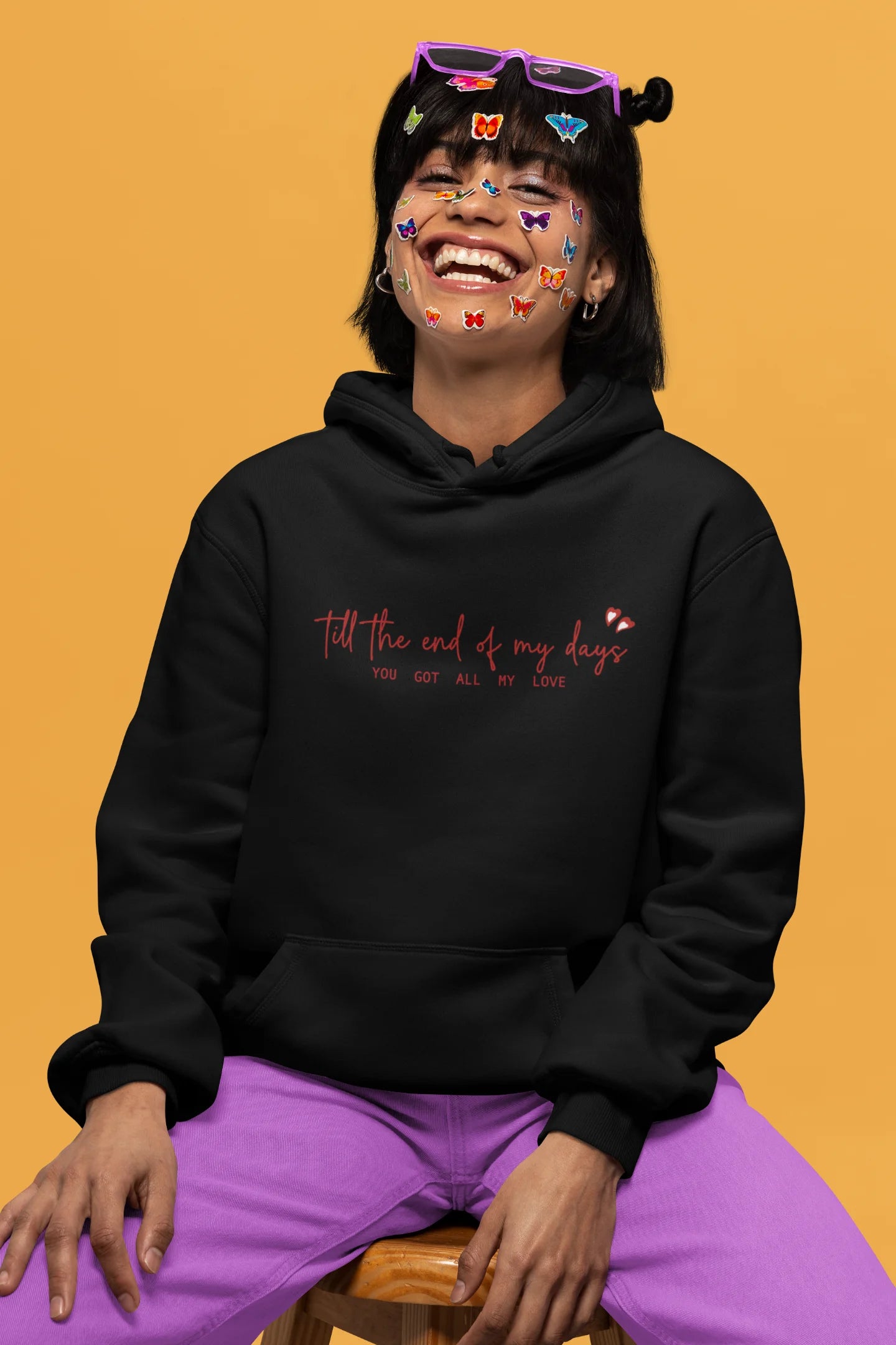 2nd front view of a female model wearing a black hoodie with a heart design and the text "All My Love".