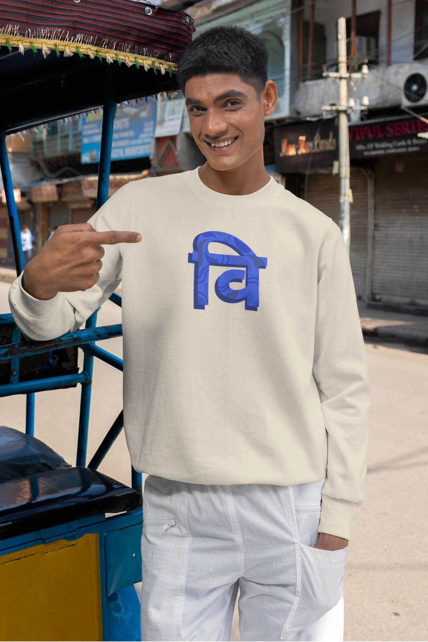 3rd front view of a male model wearing a cream sweatshirt with the phrase "Vichitra Pranee" (meaning "Strange being" or "alien") in a stylish Hindi font.