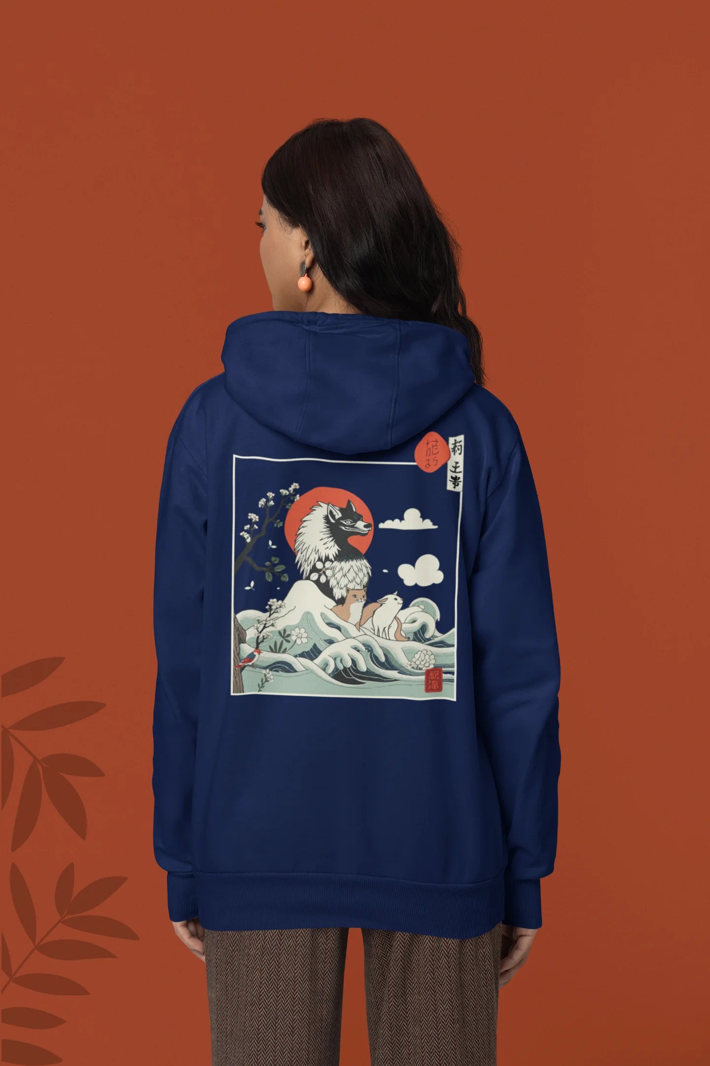 Back view of a female model wearing a navy blue hoodie with a design of a wolf surveying a Japanese landscape.
