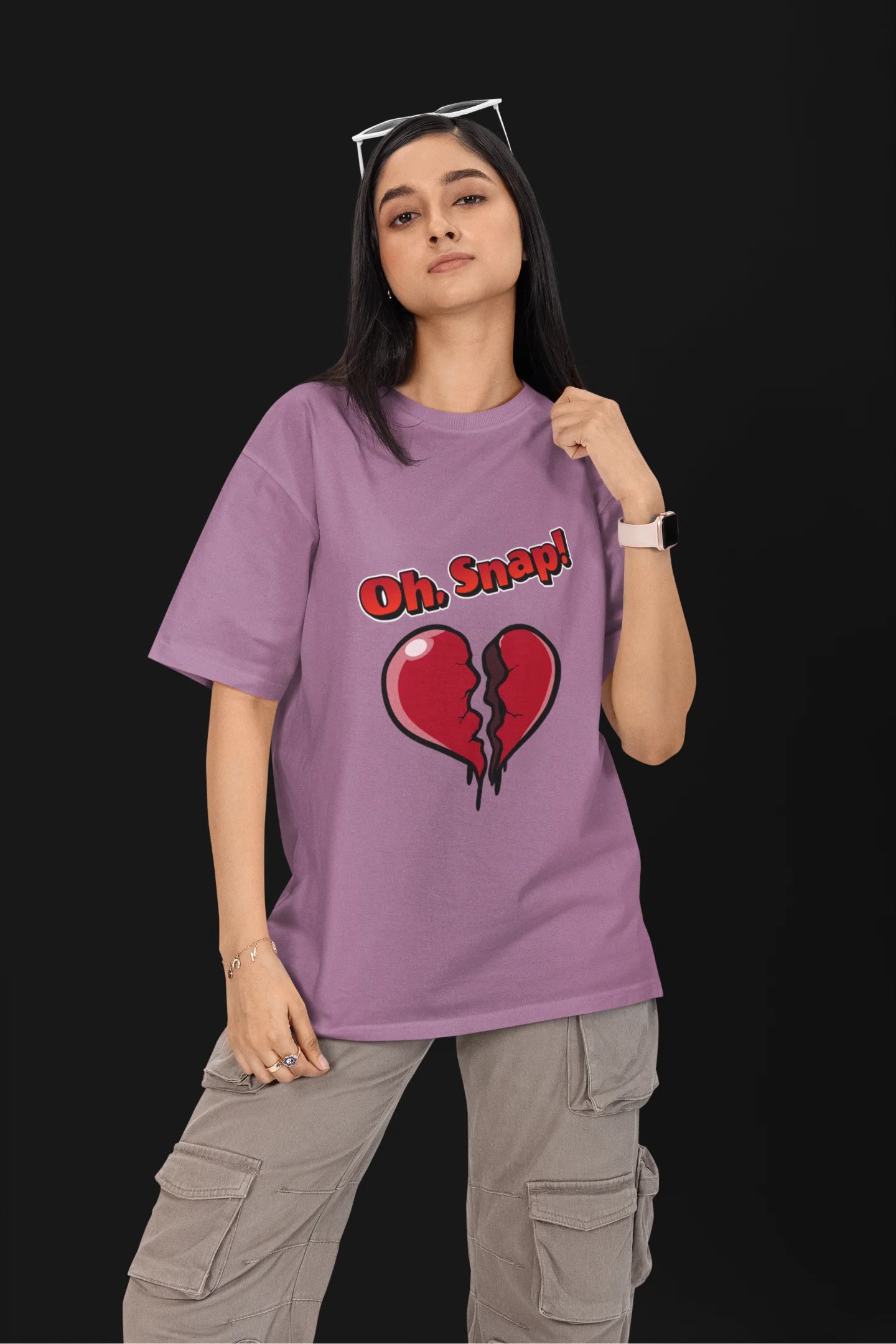 First front view of a female model wearing a dirty purple oversized t-shirt with the text "Oh Snap!" and a broken heart symbol underneath.