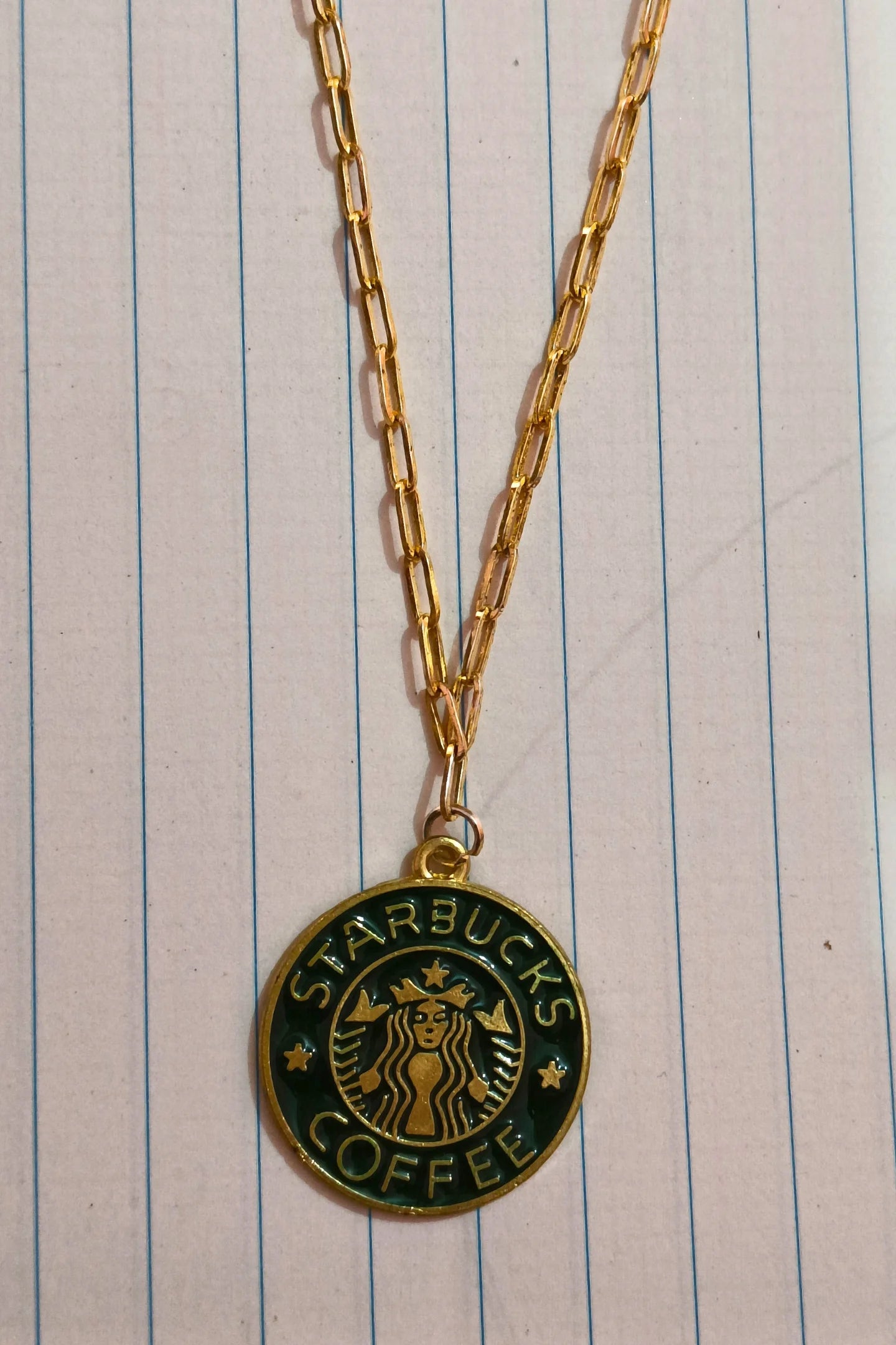 3rd view of a gold chain necklace with a small pendant featuring the Starbucks logo.