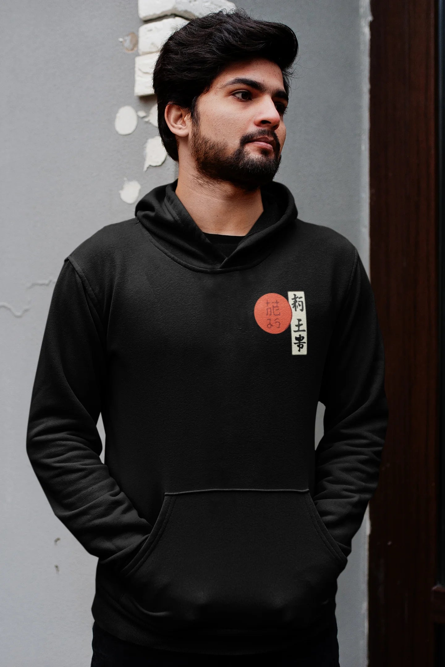 Third front view of a male model wearing a black hoodie with a design of a wolf surveying a Japanese landscape.