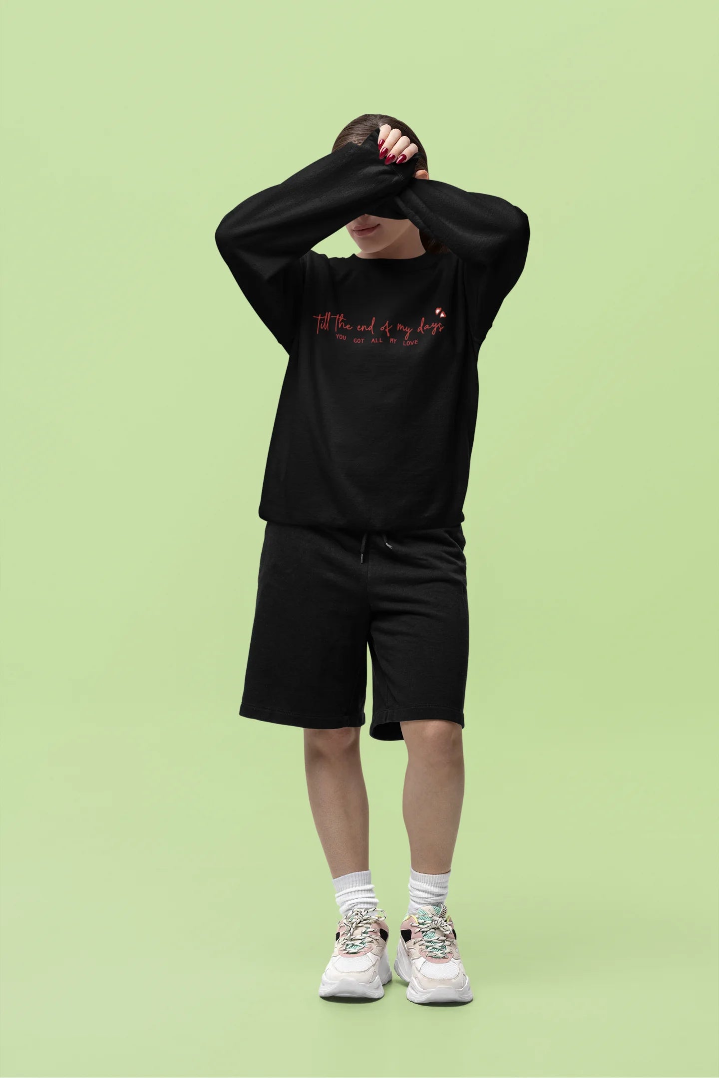 Fourth front view of a female model wearing a black sweatshirt with a heart design and the text "All My Love".
