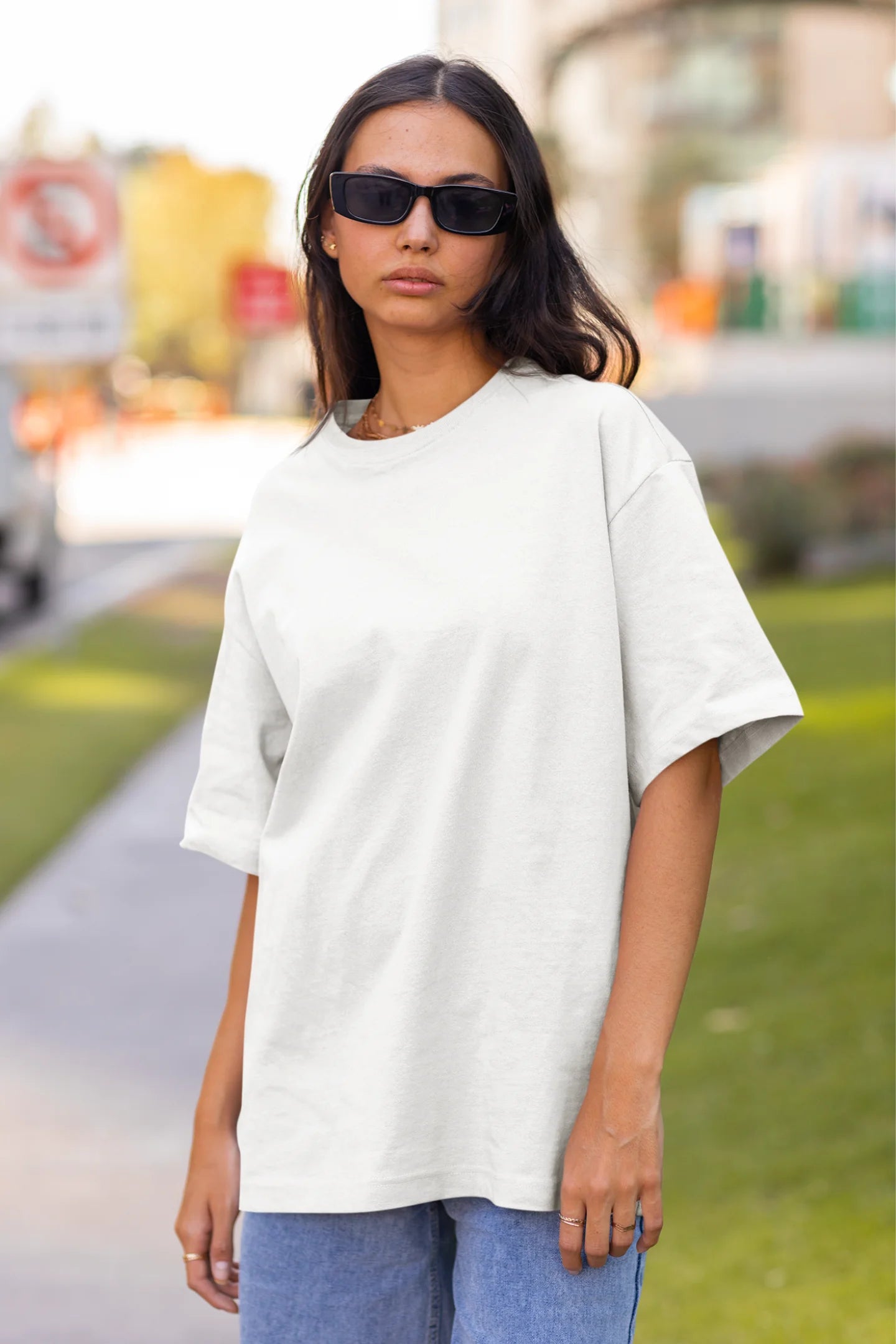 Front view of woman wearing Off White coloured Oversize T-shirt featuring Taylor Swift 1989 design on its back, Taylor's Version, and Eras Tour Merch