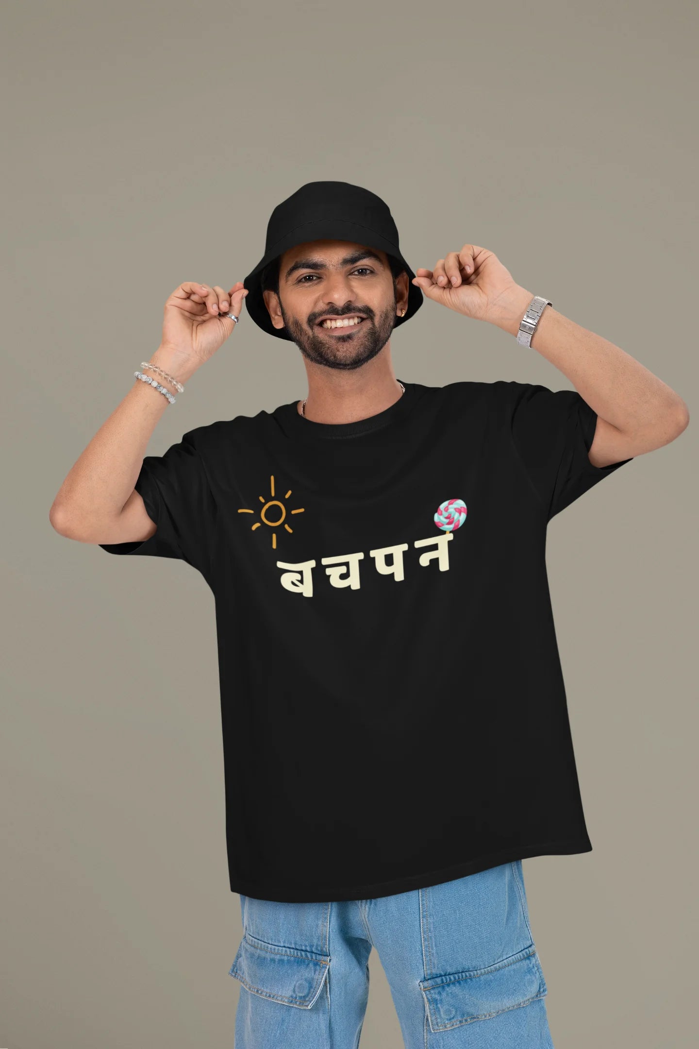 First front view of a male model wearing a black oversized t-shirt with a design representing "Bachpan" (childhood) and the concept of "Khatta Mitha" (sweet and sour).