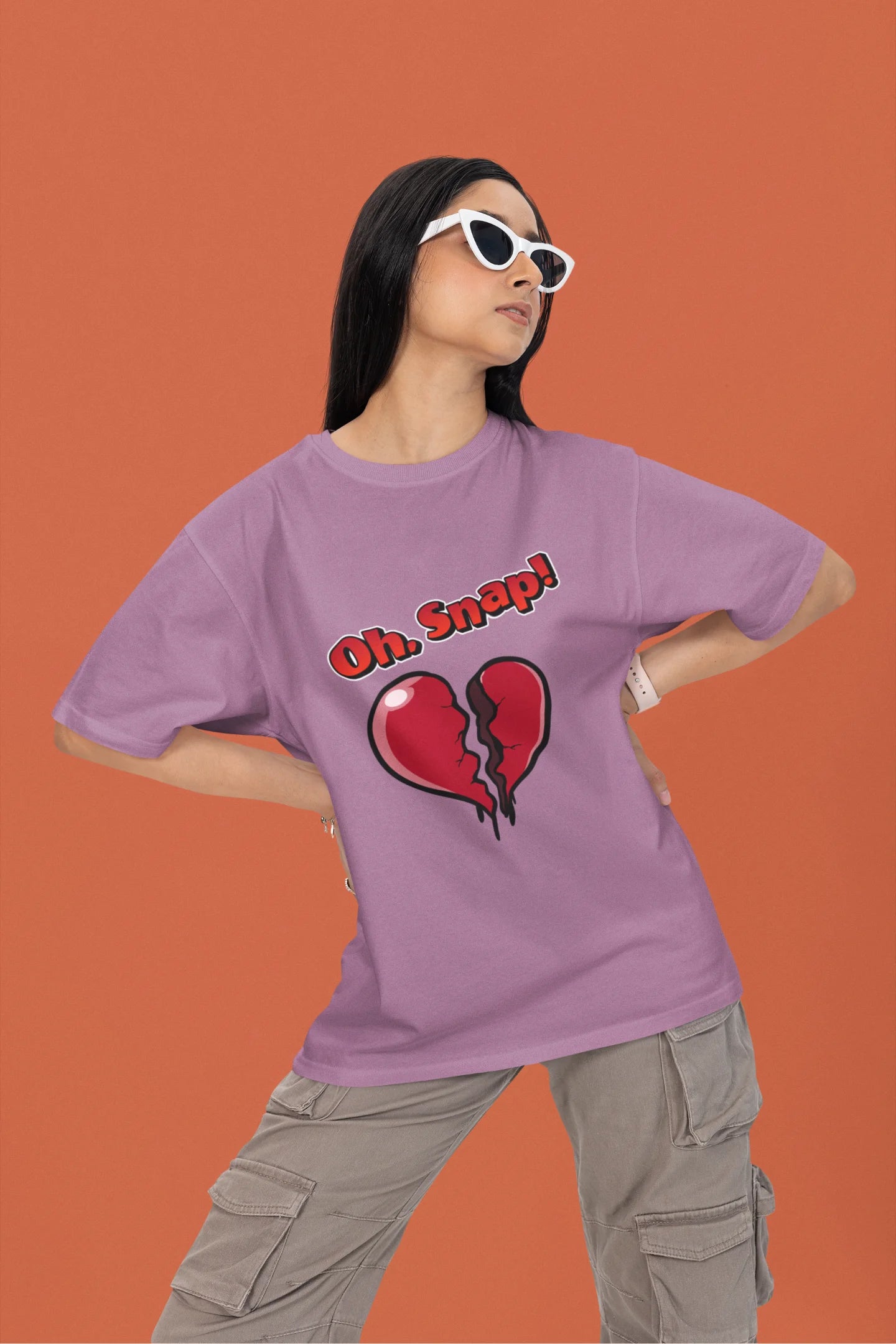 2nd front view of a female model wearing a dirty purple oversized t-shirt with the text "Oh Snap!" and a broken heart symbol underneath.