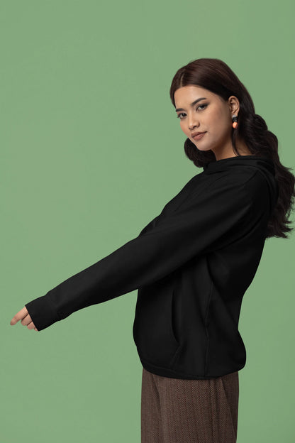 Third front view of a female model wearing a black hoodie with a design of a wolf surveying a Japanese landscape.