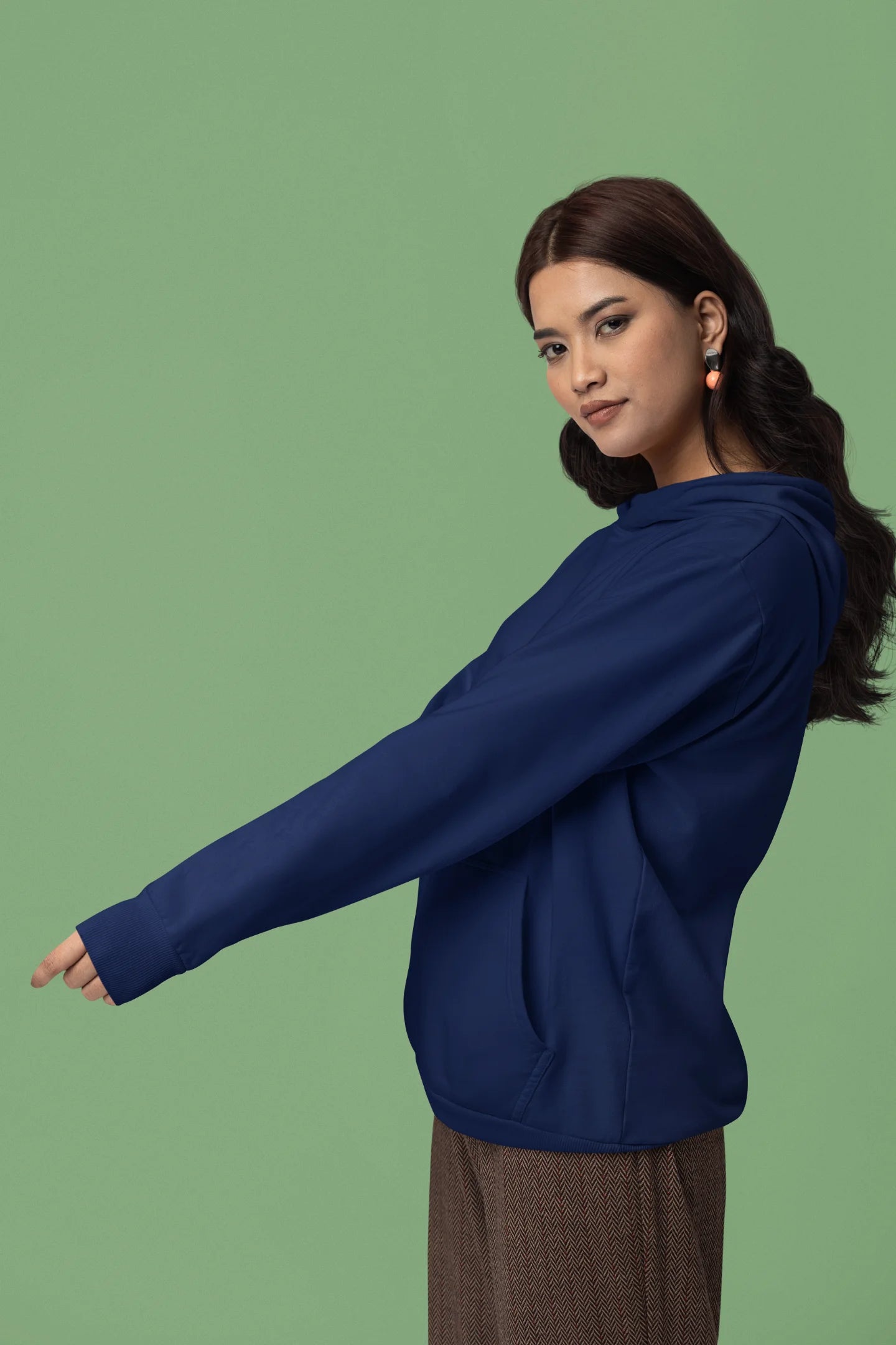 Third front view of a female model wearing a navy blue hoodie with a design of a wolf surveying a Japanese landscape.