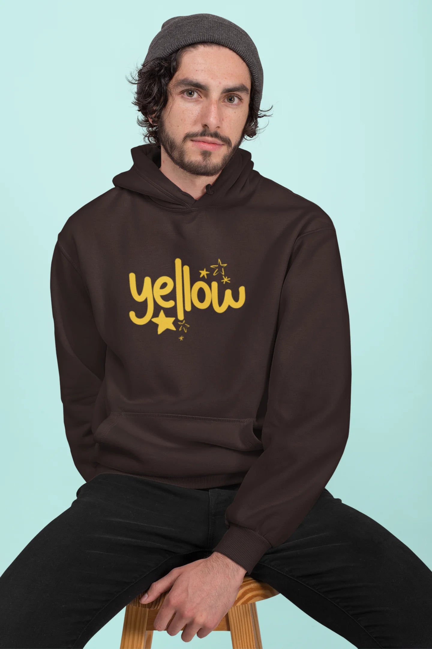 2nd front view of a male model wearing a chocolate brown hoodie with the "Yellow" album artwork by Coldplay.
