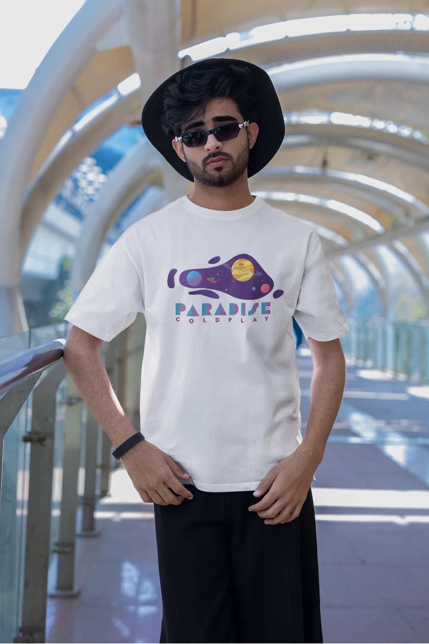 Second front view of a male model wearing an white oversized t-shirt with the "Paradise" album artwork by Coldplay.
