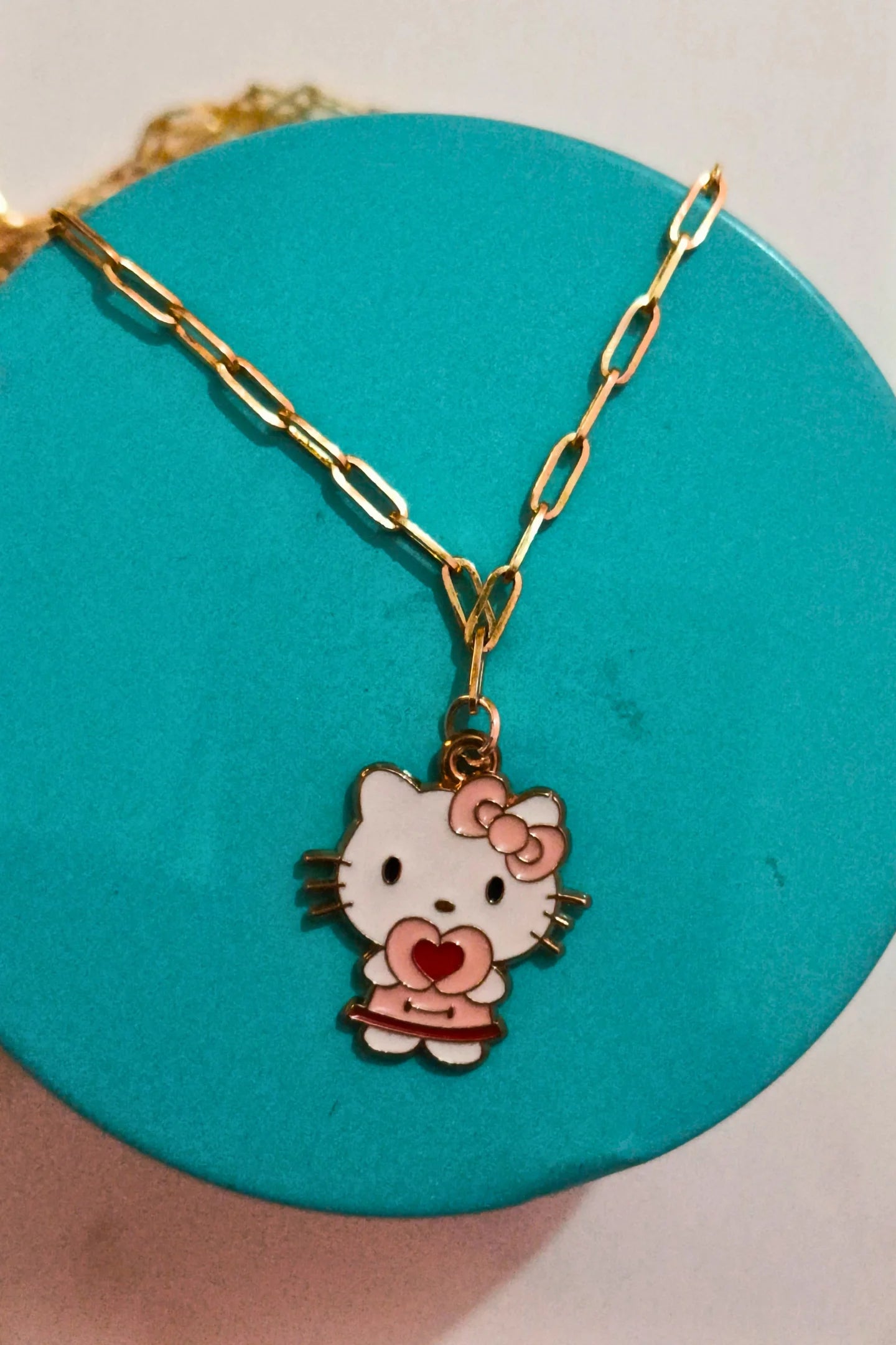 First front view of gold chain necklace with a small pendant shaped like Hello Kitty with a heart sign.