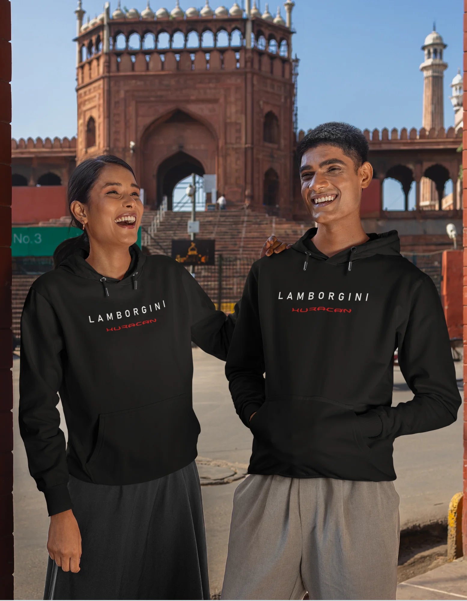 Front view of a female and male model wearing a black hoodie featuring a Lamborghini Huracan design, exuding speed and power.