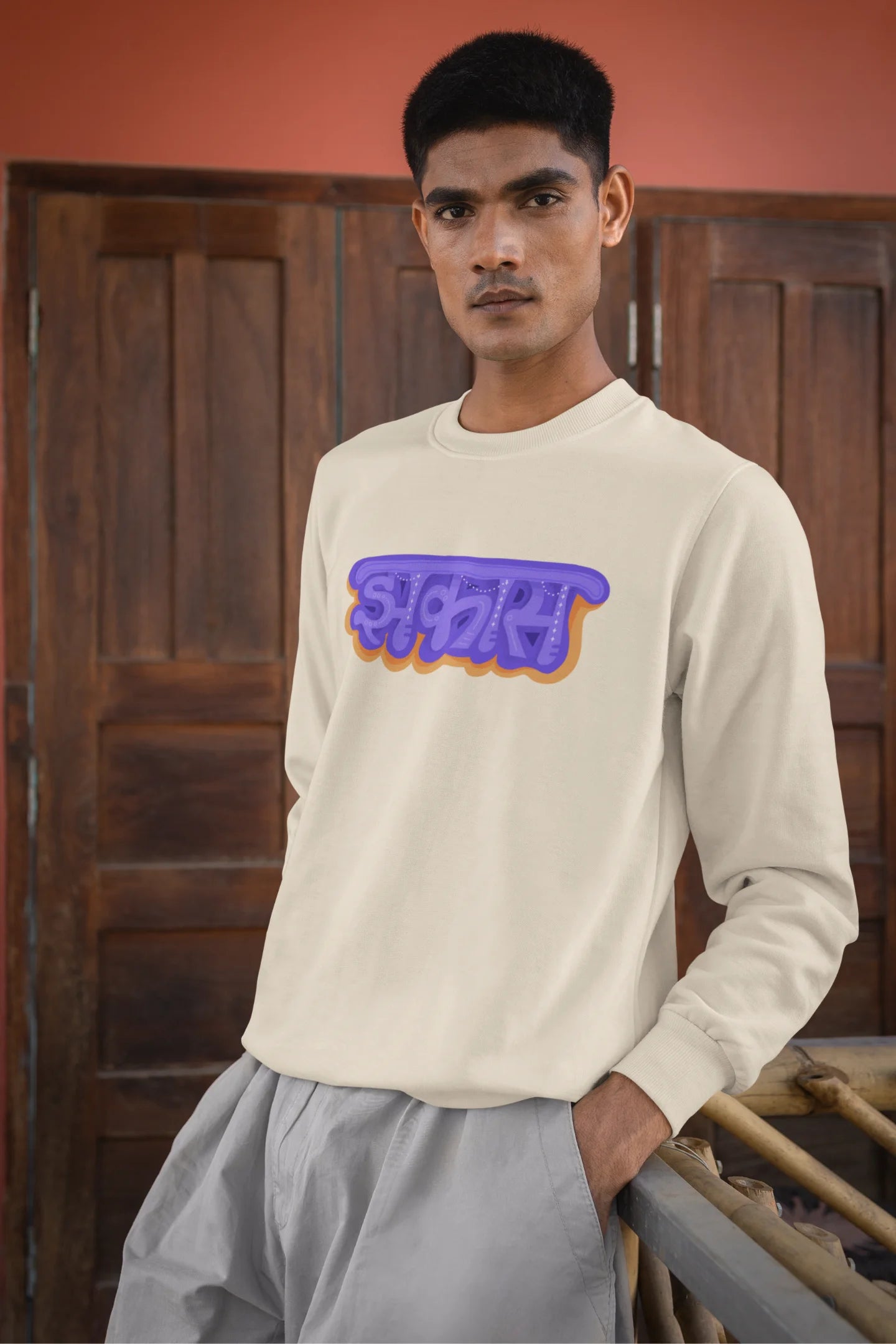 3rd front view of a male model wearing an cream sweatshirt featuring "Jhakas" in a stylish font.