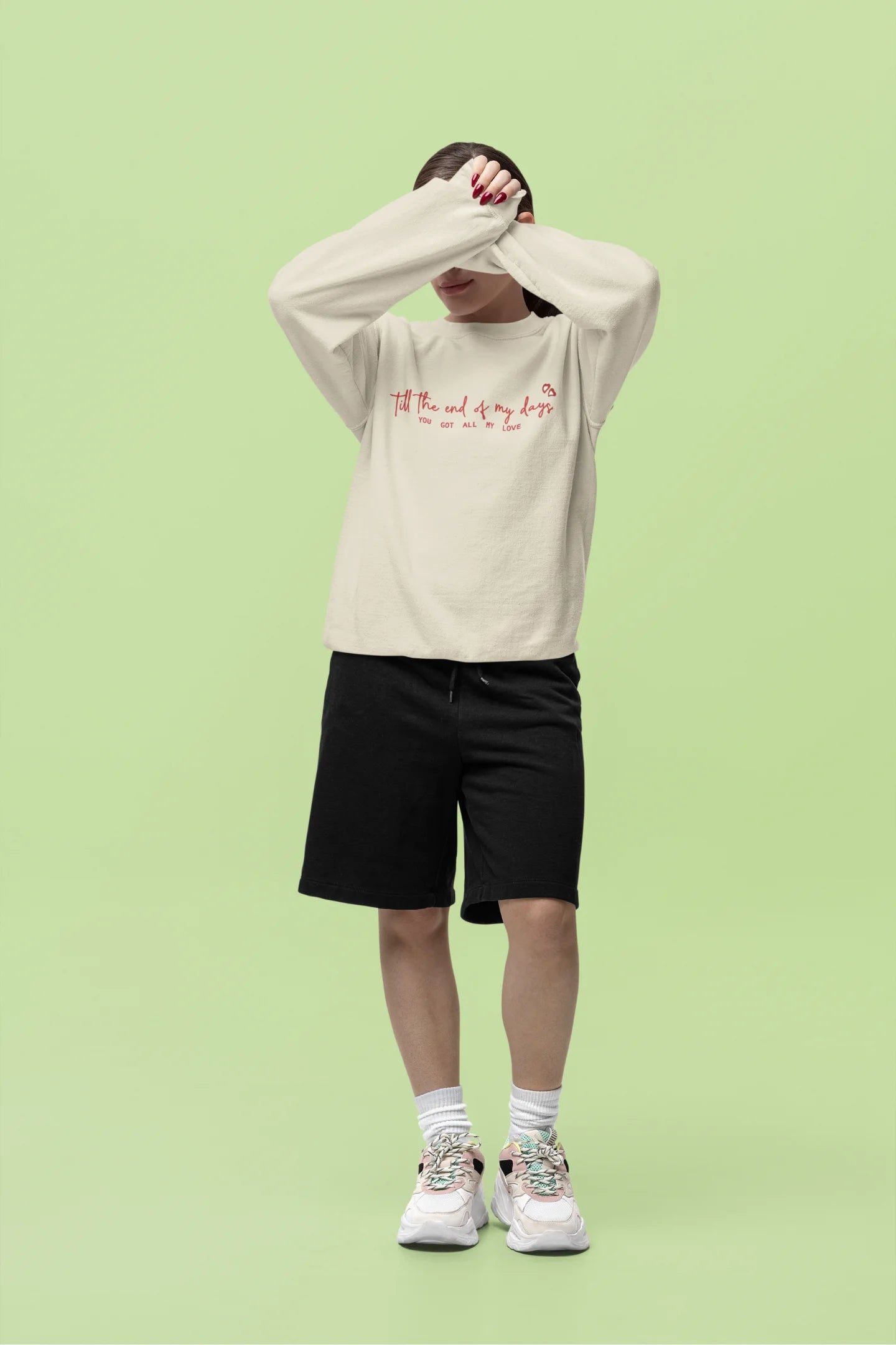 Fourth front view of a female model wearing a cream sweatshirt with a heart design and the text "All My Love".