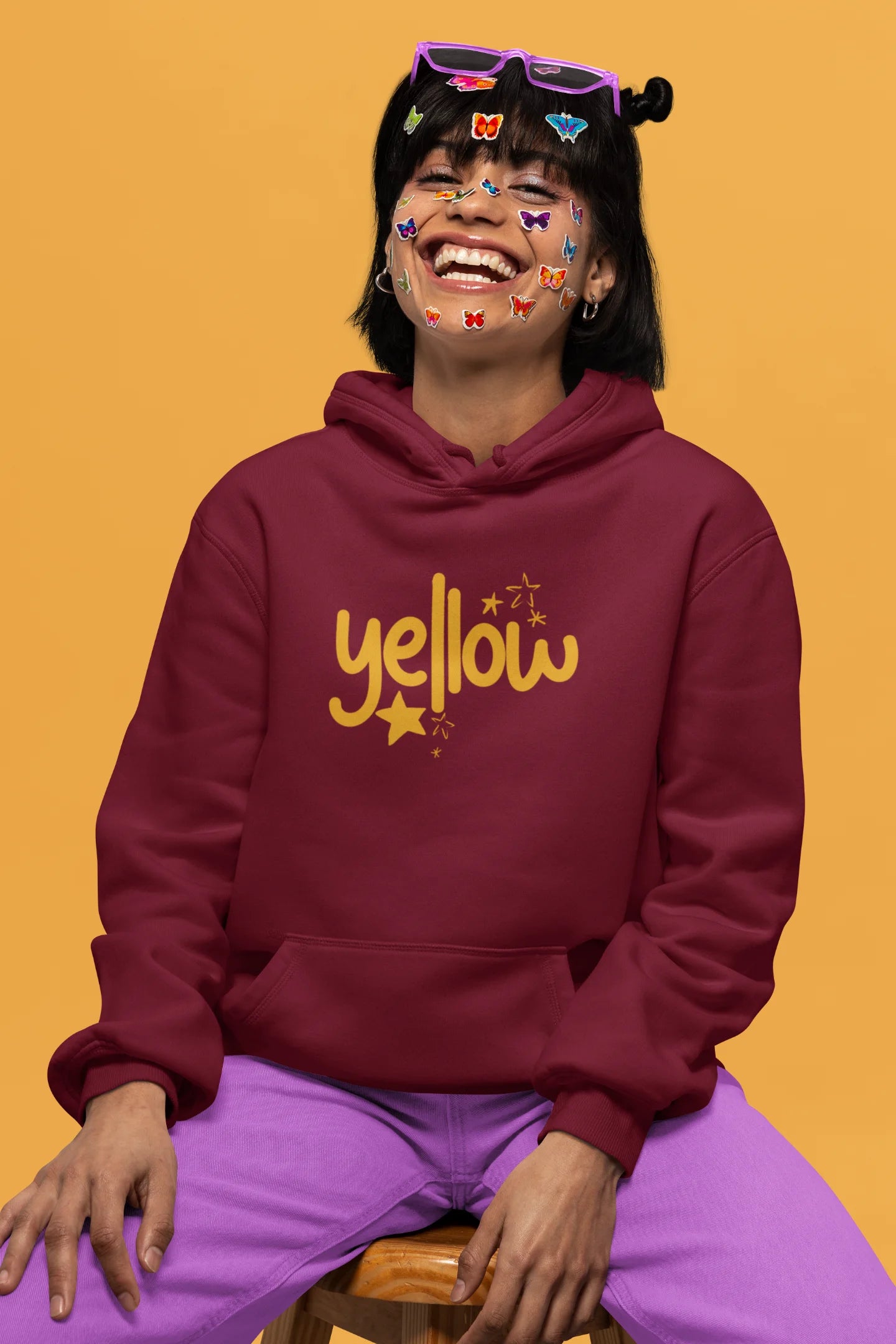 First front view of a female model wearing a maroon hoodie with the "Yellow" album artwork by Coldplay.