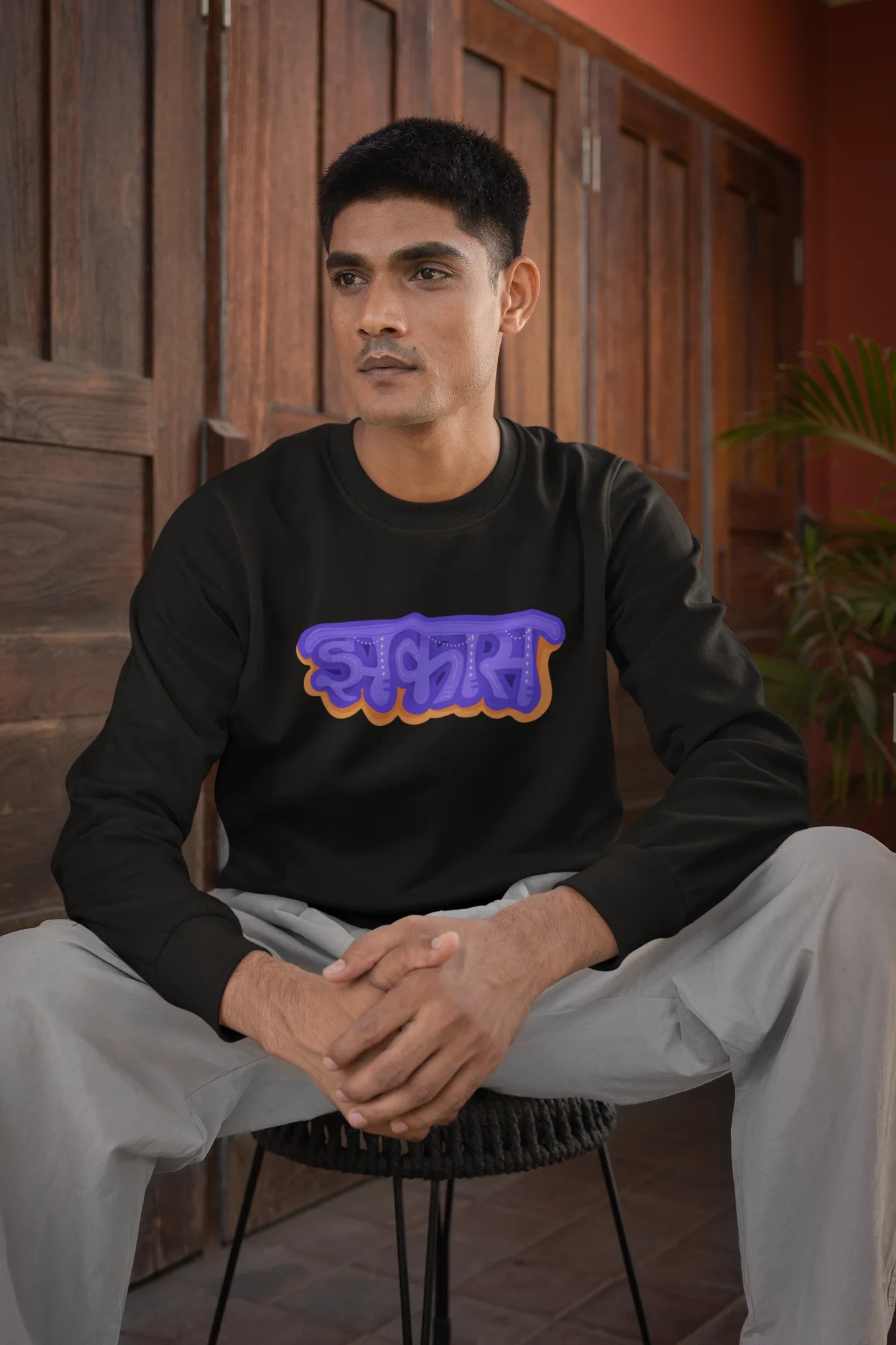 First front view of a male model wearing an black sweatshirt featuring "Jhakas" in a stylish font.