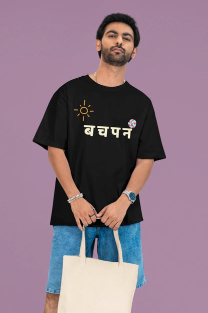 2nd front view of a male model wearing a black oversized t-shirt with a design representing "Bachpan" (childhood) and the concept of "Khatta Mitha" (sweet and sour).