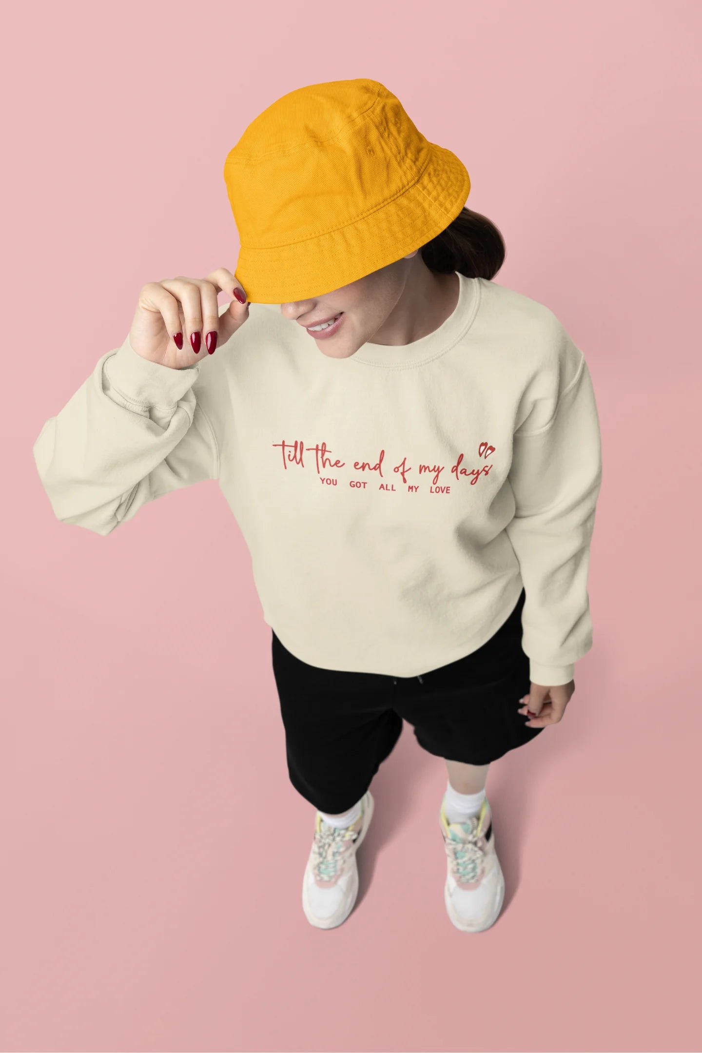 Third front view of a female model wearing a cream sweatshirt with a heart design and the text "All My Love".