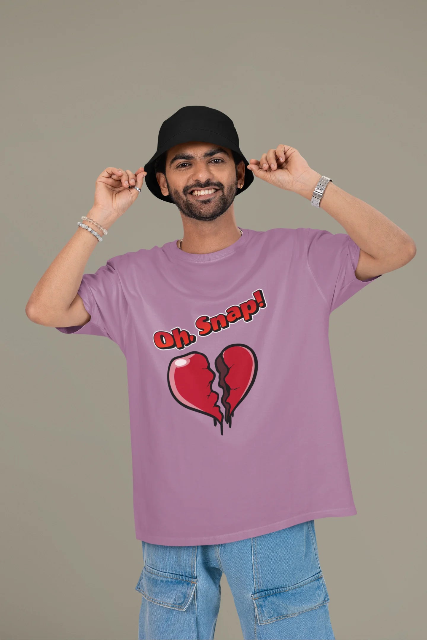 First front view of a male model wearing a dirty purple oversized t-shirt with the text "Oh Snap!" and a broken heart symbol underneath.