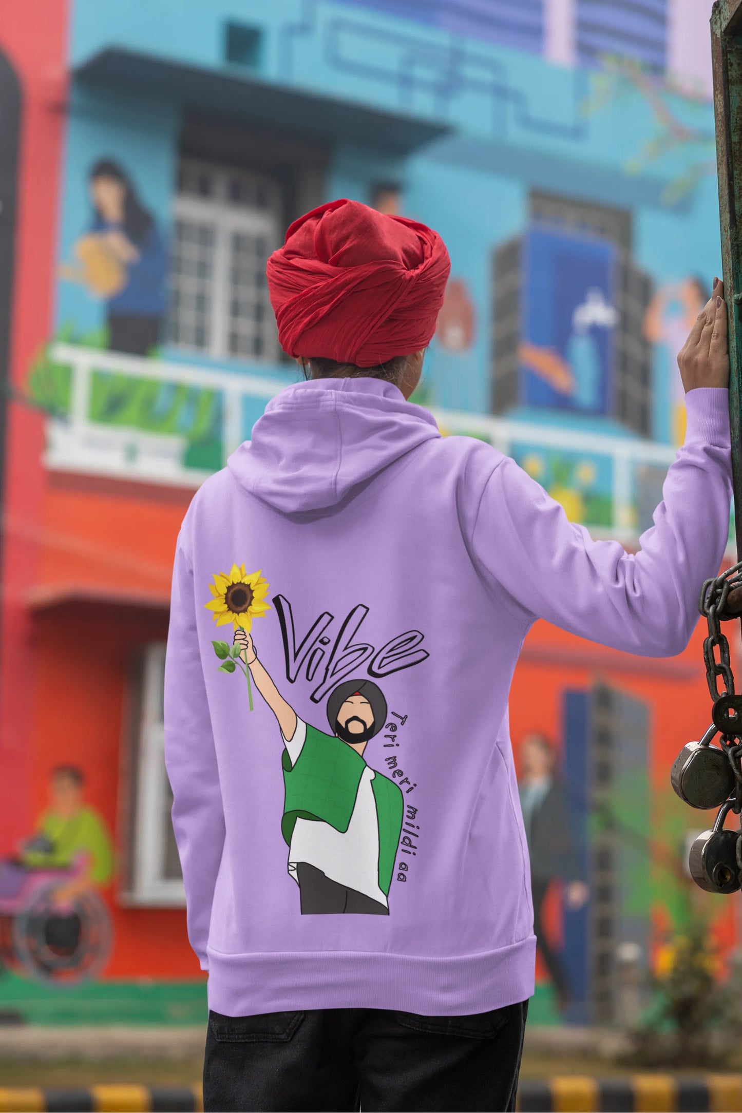 Back view of a female model wearing a comfortable dirty purple hoodie featuring the phrase "Vibe Teri Meri" in a modern font on a portrait of Diljit Singh holding up a sunflower, perfect for expressing your unique style and feeling the rhythm.