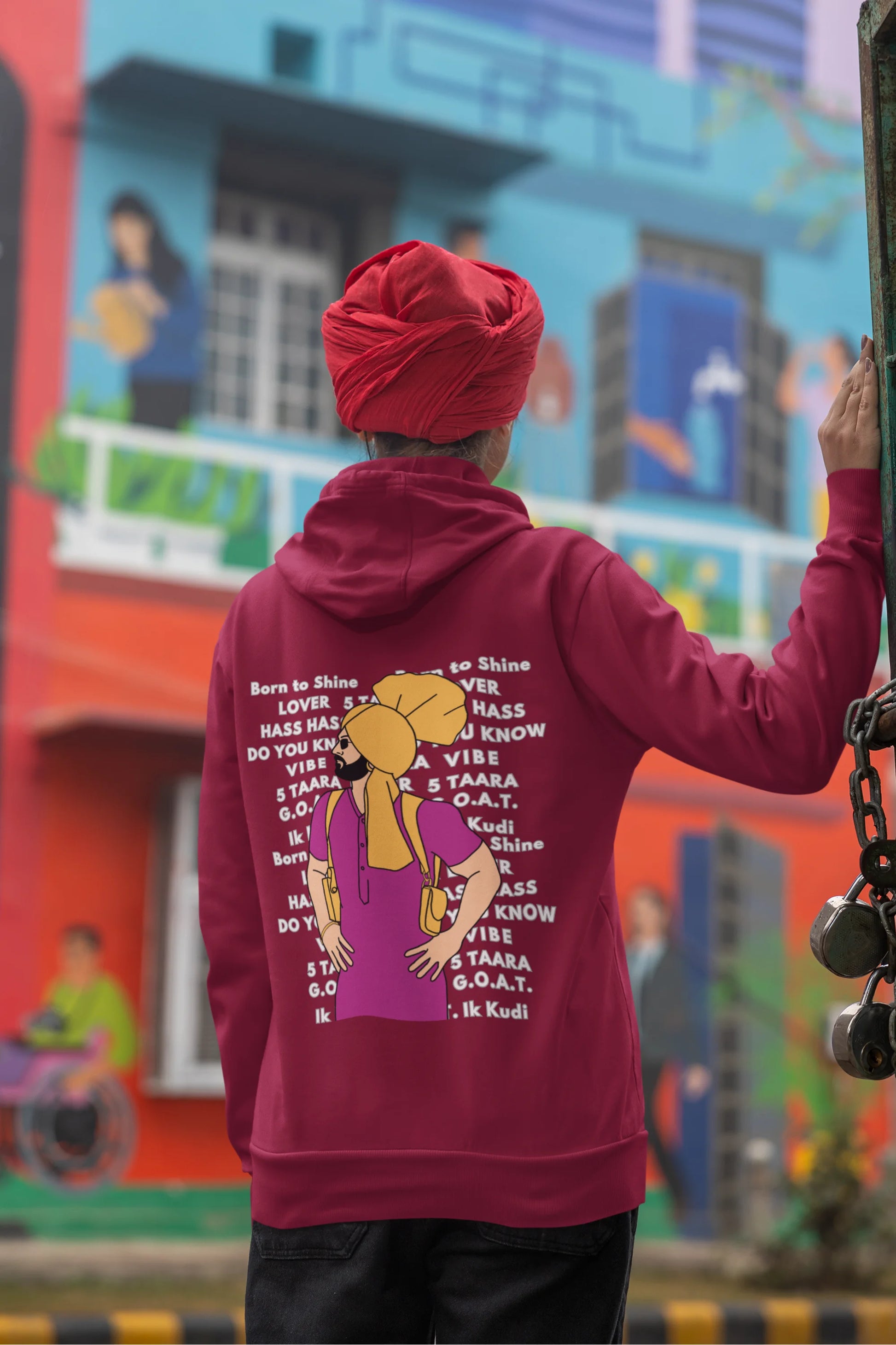 Back view of a female model wearing a maroon hoodie with a portrait of Diljit Dosanjh and lyrics from the song "Ikk Kudi."