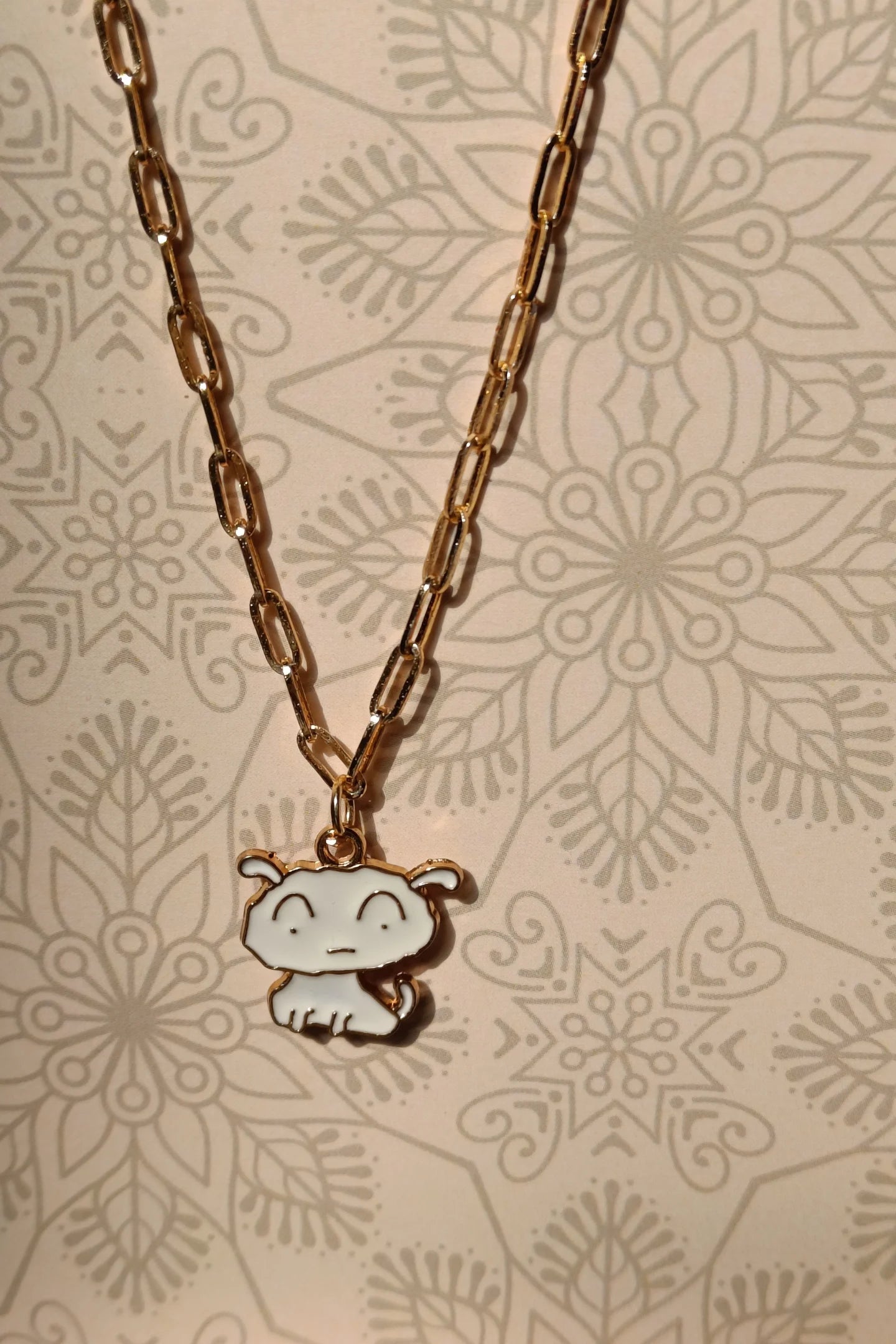 First view of a gold chain necklace with a small pendant depicting Shero from the anime Shin Chan.