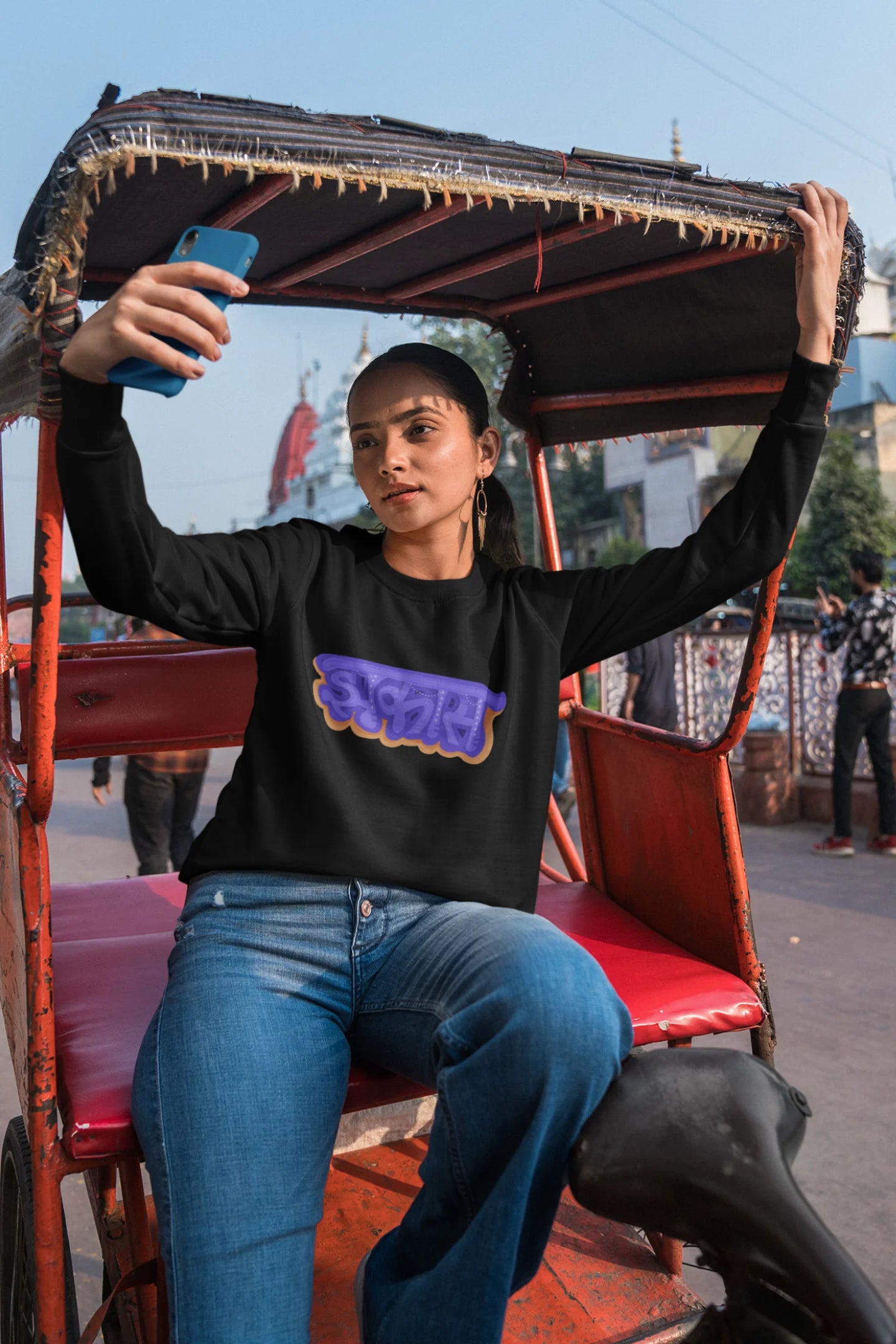 First front view of a female model wearing an black sweatshirt featuring "Jhakas" in a stylish font.