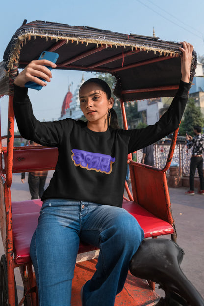 First front view of a female model wearing an black sweatshirt featuring "Jhakas" in a stylish font.