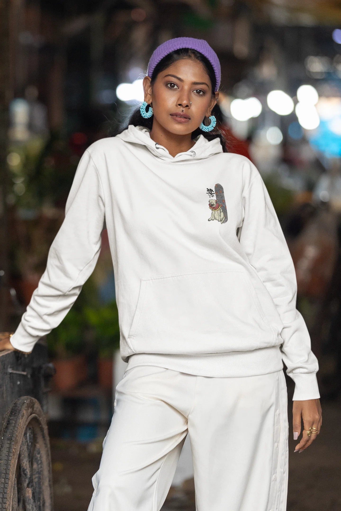 Fourth front view of a female model wearing a cream hoodie with a design of a mythical Japanese dog.
