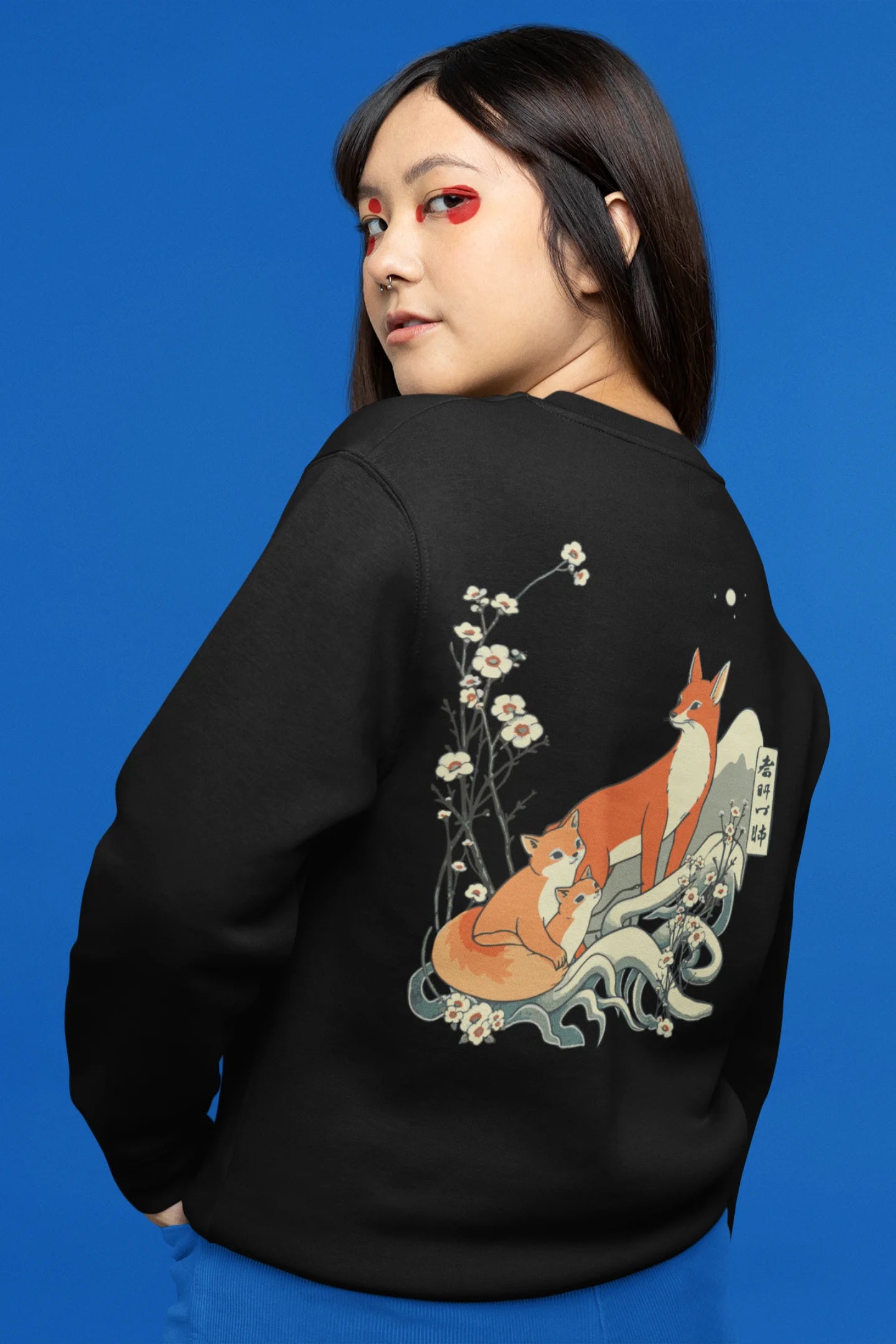 Back view female model wearing a black sweatshirt with a design of a fox and its cub in a traditional Japanese landscape.