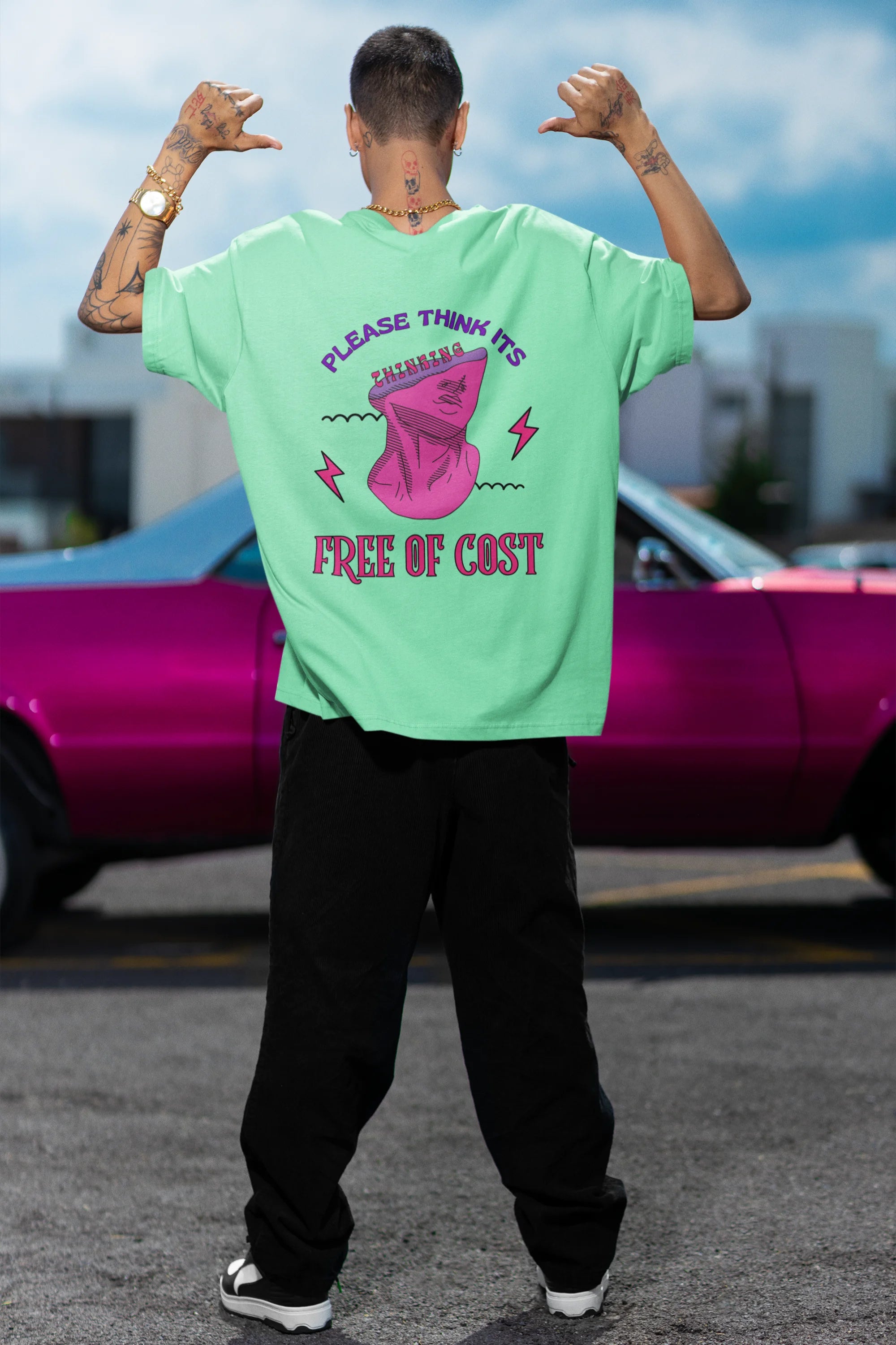 Back view of a male model wearing an mint green oversized t-shirt featuring a thought-provoking design of a man's bust with the text "Think It's Free of Cost." Ideal for those who love funny clothing and the importance of mindful communication.