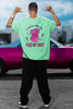 Back view of a male model wearing an mint green oversized t-shirt featuring a thought-provoking design of a man's bust with the text 