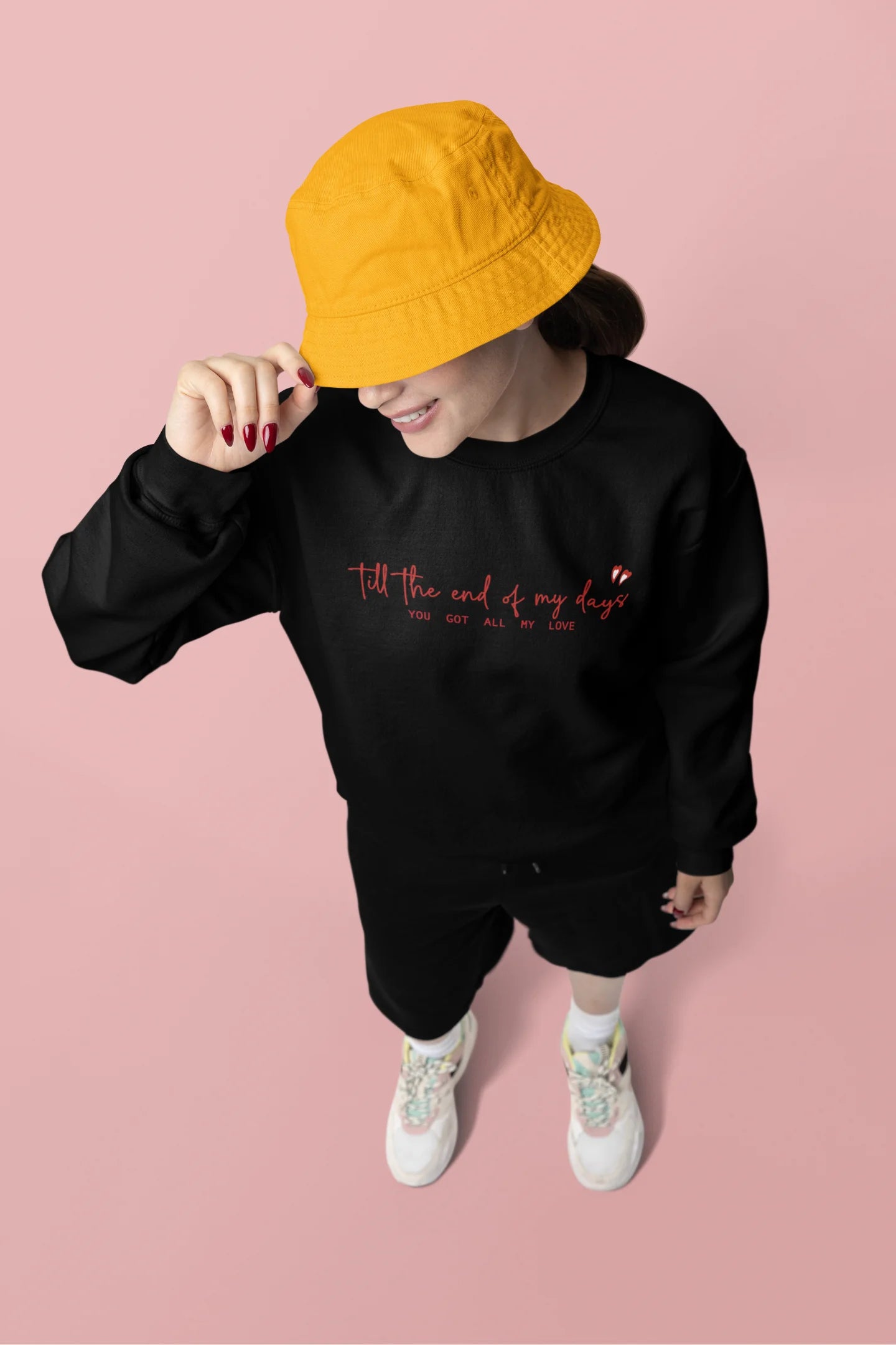 Third front view of a female model wearing a black sweatshirt with a heart design and the text "All My Love".