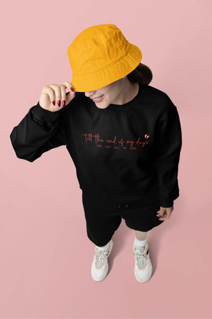 Third front view of a female model wearing a black sweatshirt with a heart design and the text "All My Love".