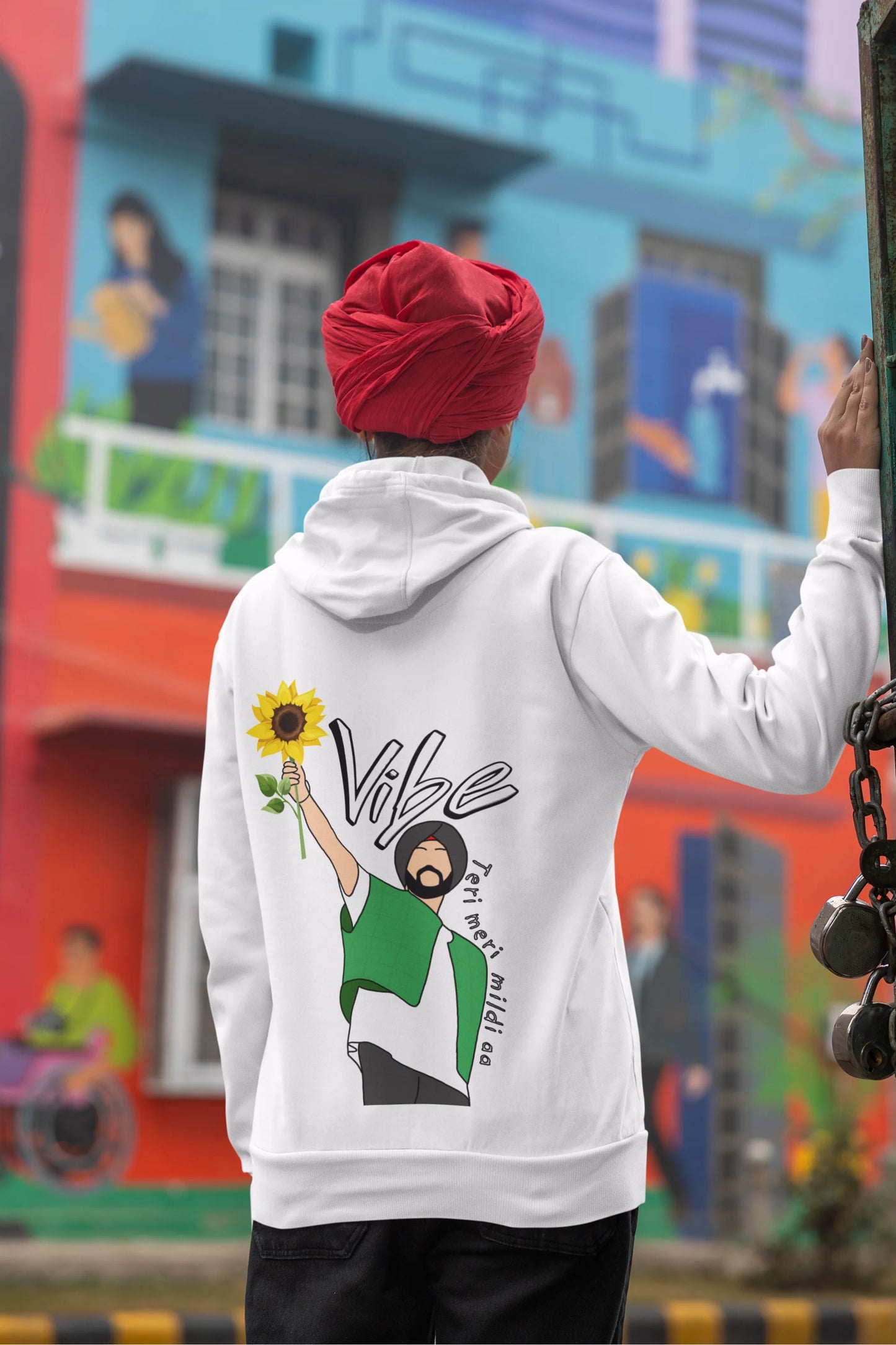 Back view of a female model wearing a comfortable white hoodie featuring the phrase "Vibe Teri Meri" in a modern font on a portrait of Diljit Singh holding up a sunflower, perfect for expressing your unique style and feeling the rhythm.