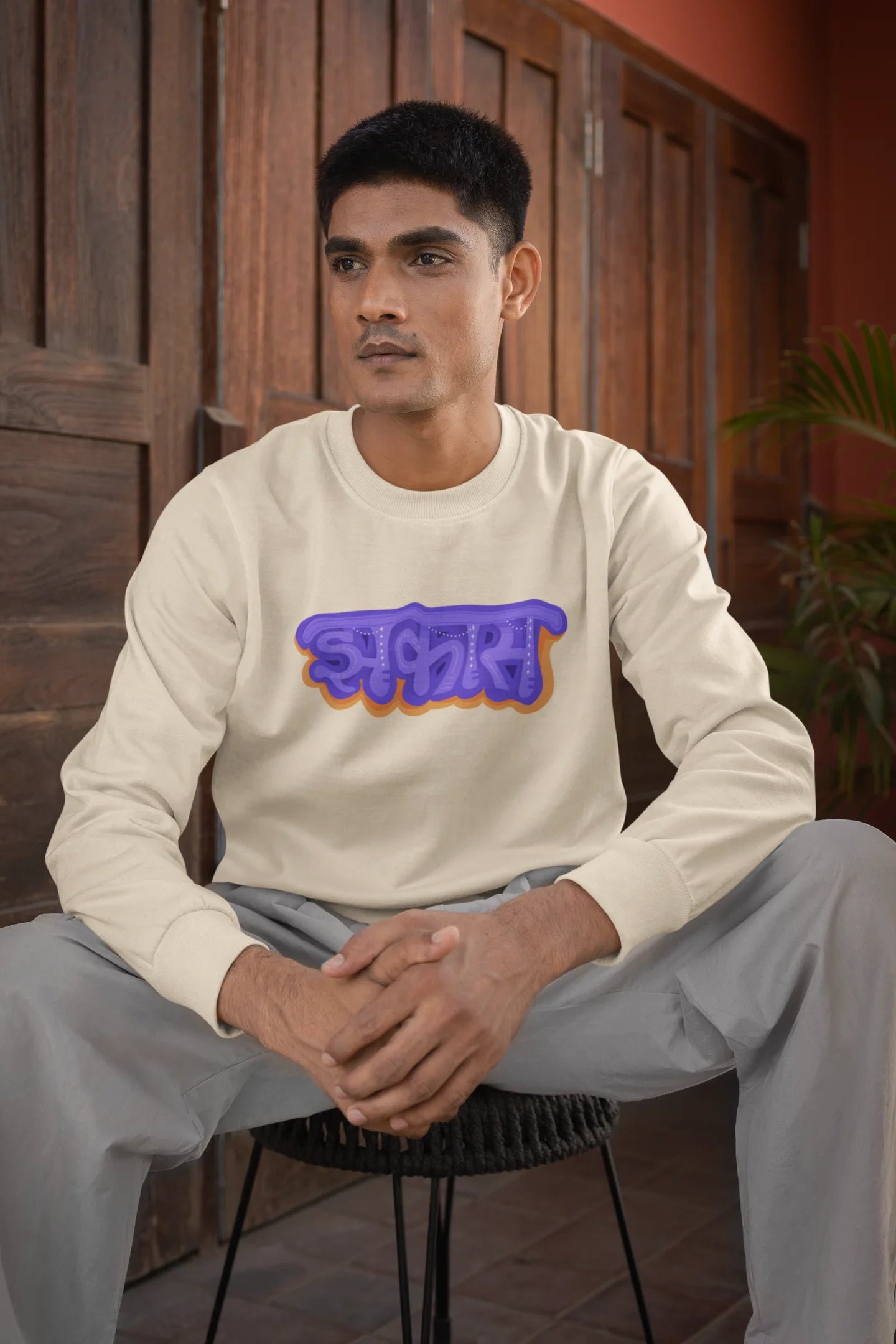 First front view of a male model wearing an cream sweatshirt featuring "Jhakas" in a stylish font.