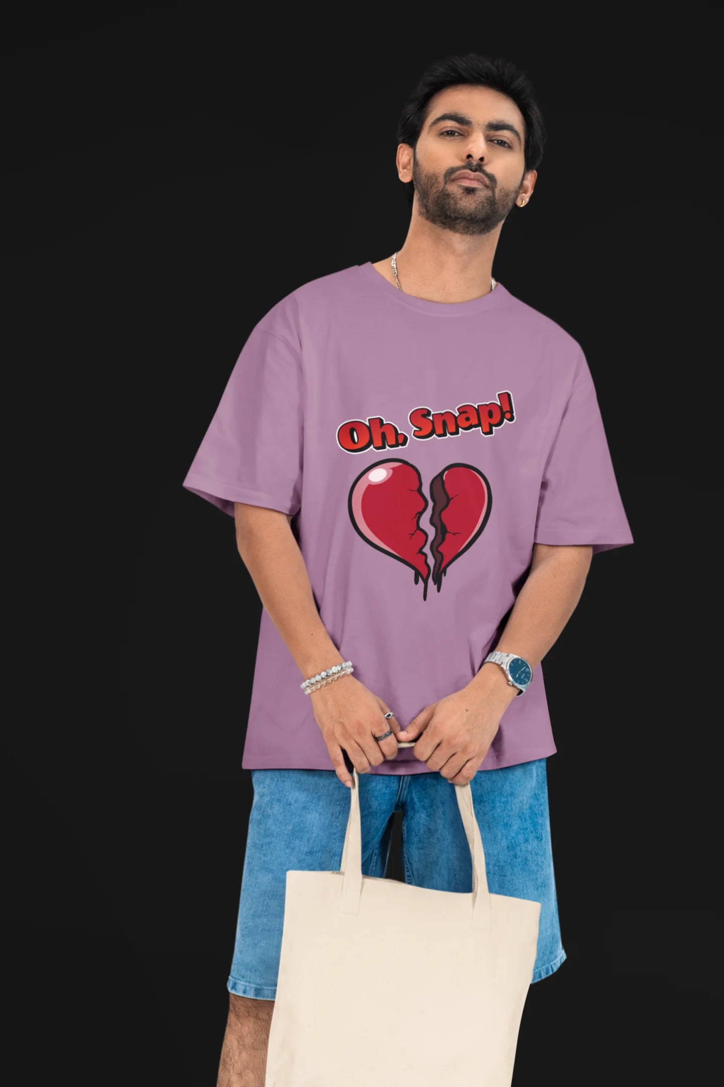 2nd front view of a male model wearing a dirty purple oversized t-shirt with the text "Oh Snap!" and a broken heart symbol underneath.