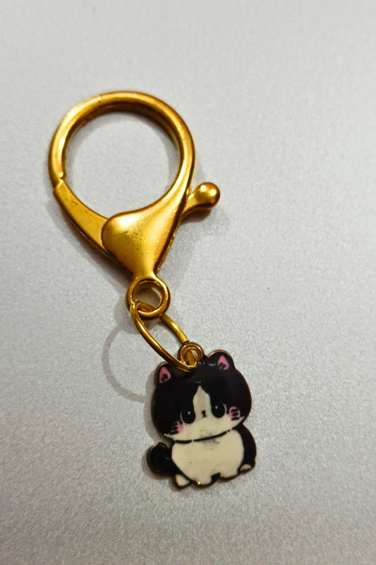 A view of a couples keychain featuring two separate charms: one of a black cat
