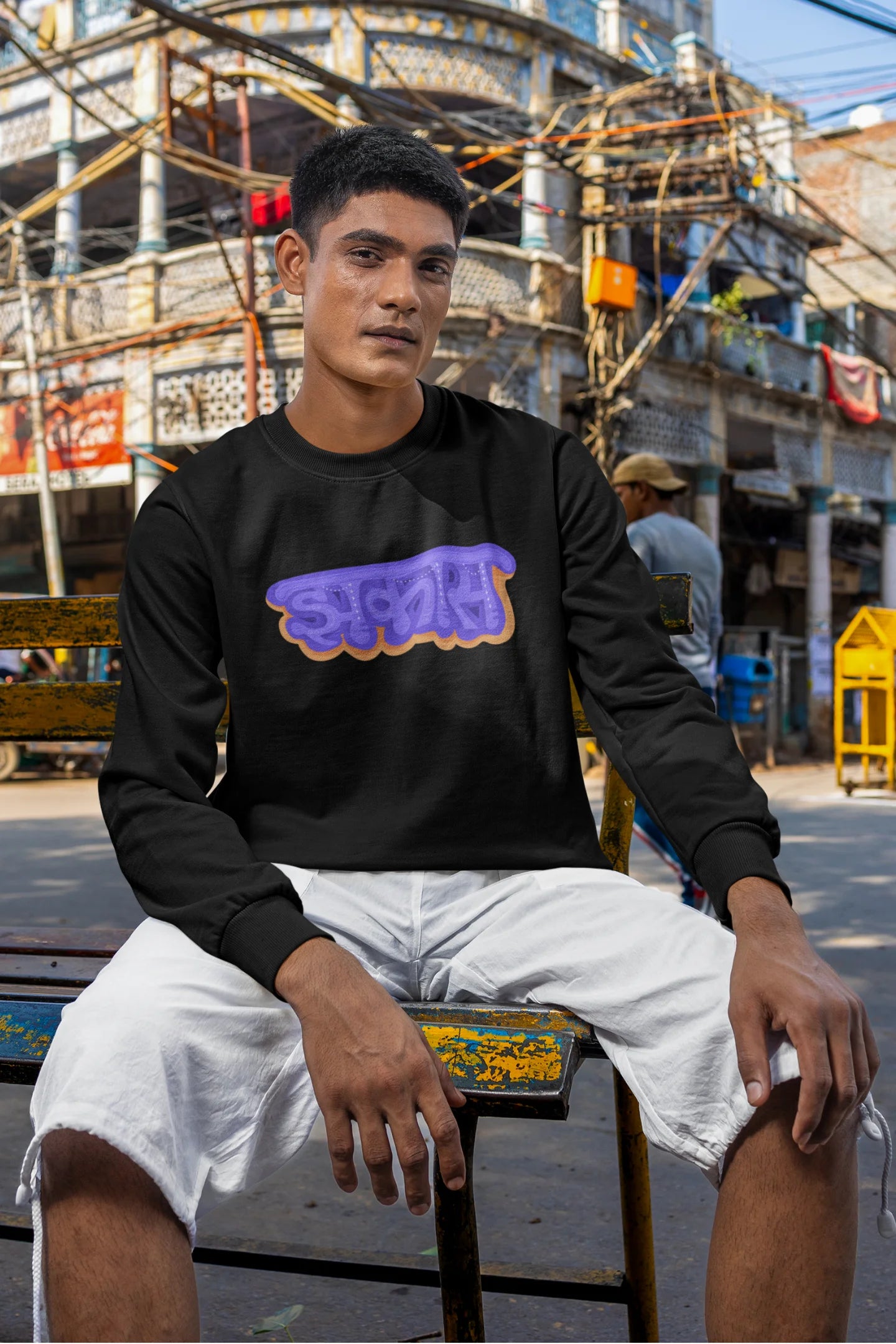 4th front view of a male model wearing an black sweatshirt featuring "Jhakas" in a stylish font.