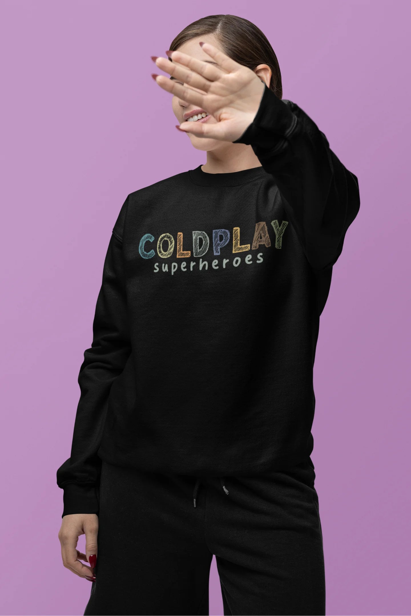 Third front view of a female model wearing an black sweatshirt with a design inspired by the "Something Just Like This" music video, featuring the word "Superheroes".