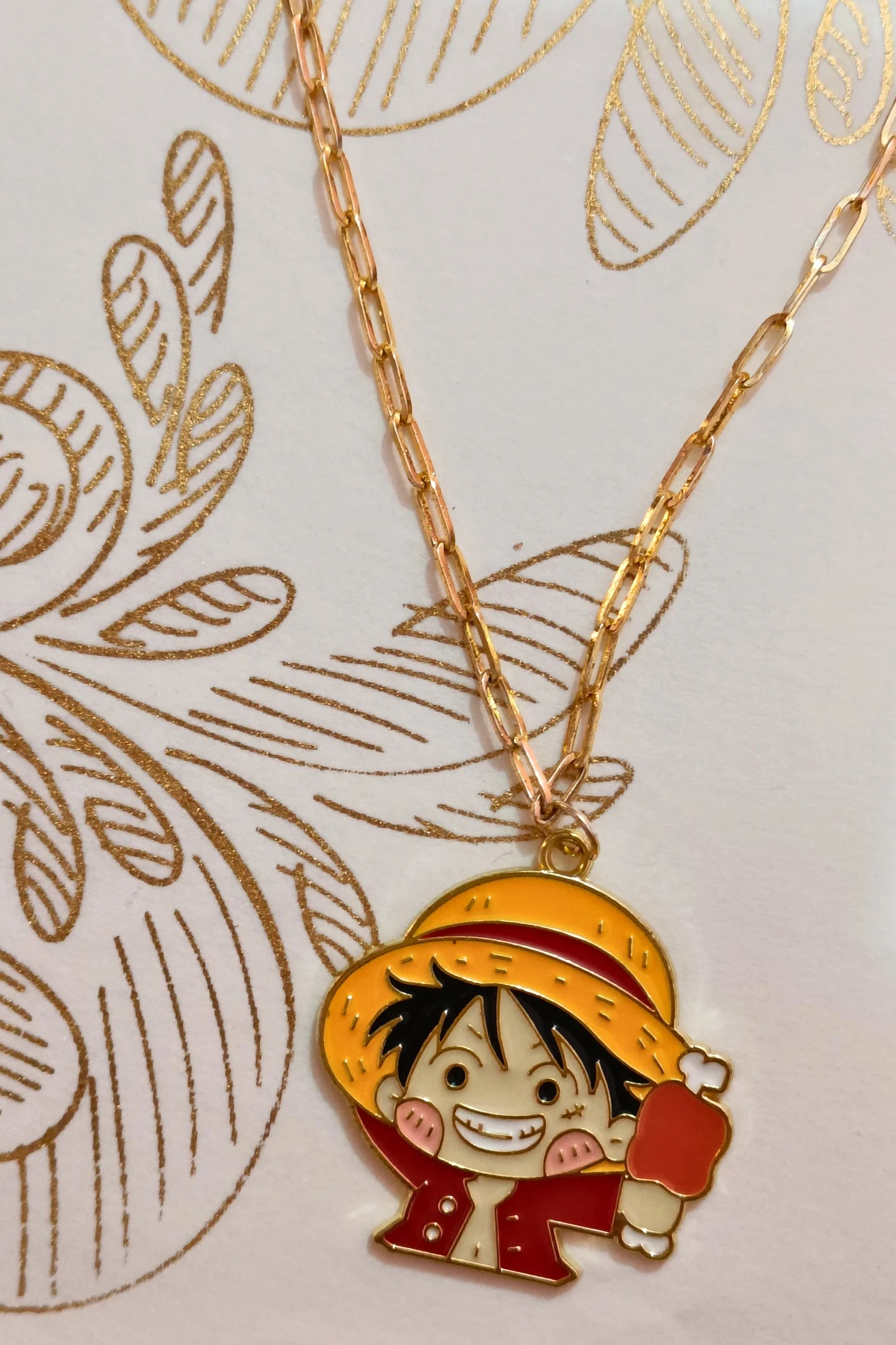 4th view of a gold chain necklace with a small pendant depicting Luffy from One Piece eating meat.