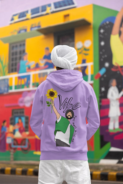 Back view of a male model wearing a comfortable dirty purple hoodie featuring the phrase "Vibe Teri Meri" in a modern font on a portrait of Diljit Singh holding up a sunflower, perfect for expressing your unique style and feeling the rhythm.