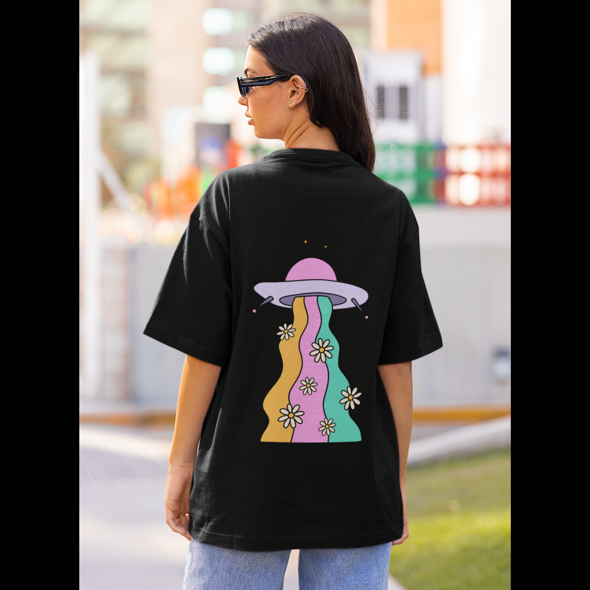 Back view of a female model wearing a black oversized t-shirt featuring a fun "Space Wreck" design with elements of spaceships, UFOs, and a hint of extraterrestrial life.