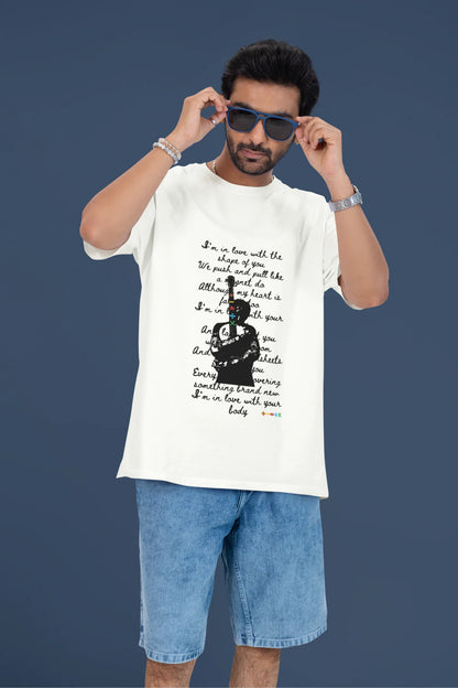 4th front view of a male model wearing a off-white oversized t-shirt featuring a design inspired by Ed Sheeran's concerts, related to the song "Shape of You."
