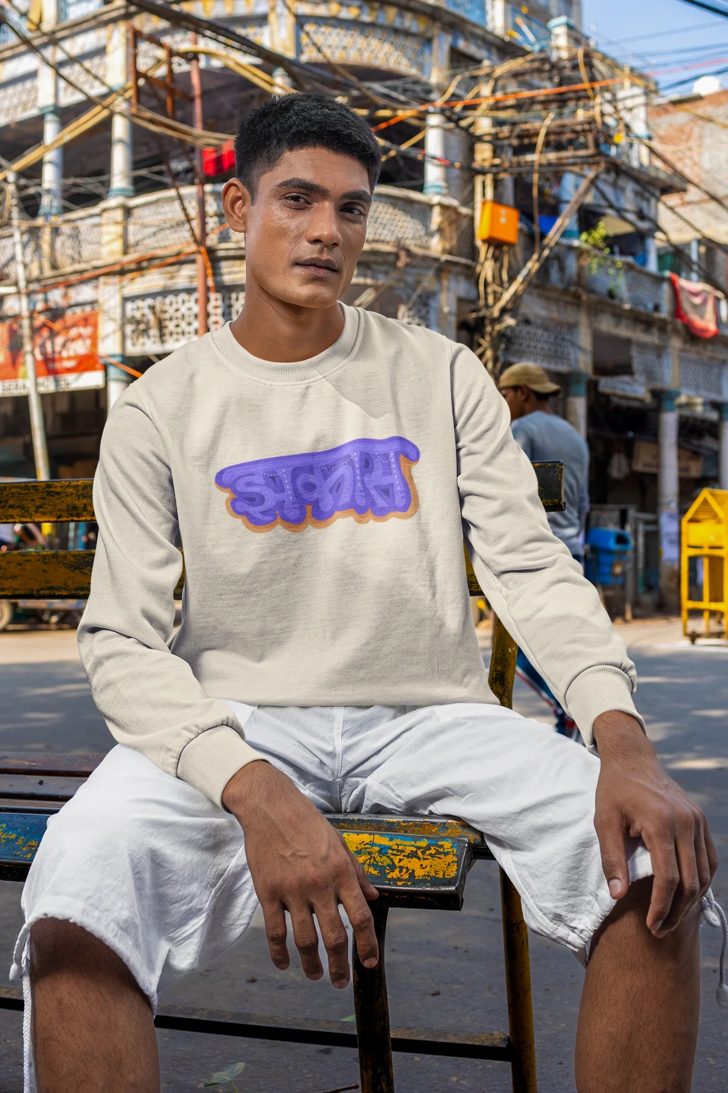 2nd front view of a male model wearing an cream sweatshirt featuring "Jhakas" in a stylish font.