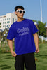 Front view of the man of the couple wearing matching royal blue oversize tees, one with 