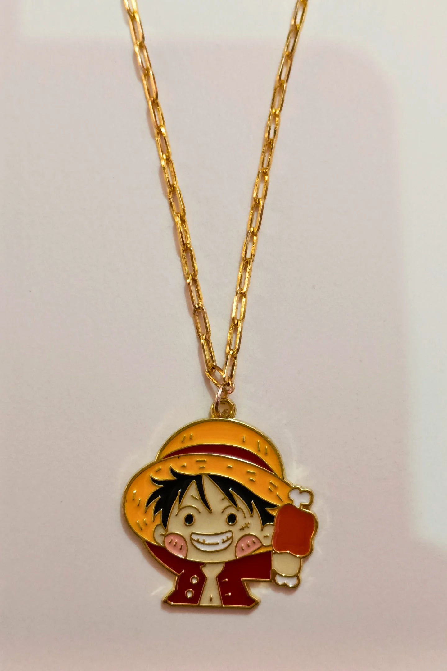 3rd view of a gold chain necklace with a small pendant depicting Luffy from One Piece eating meat.