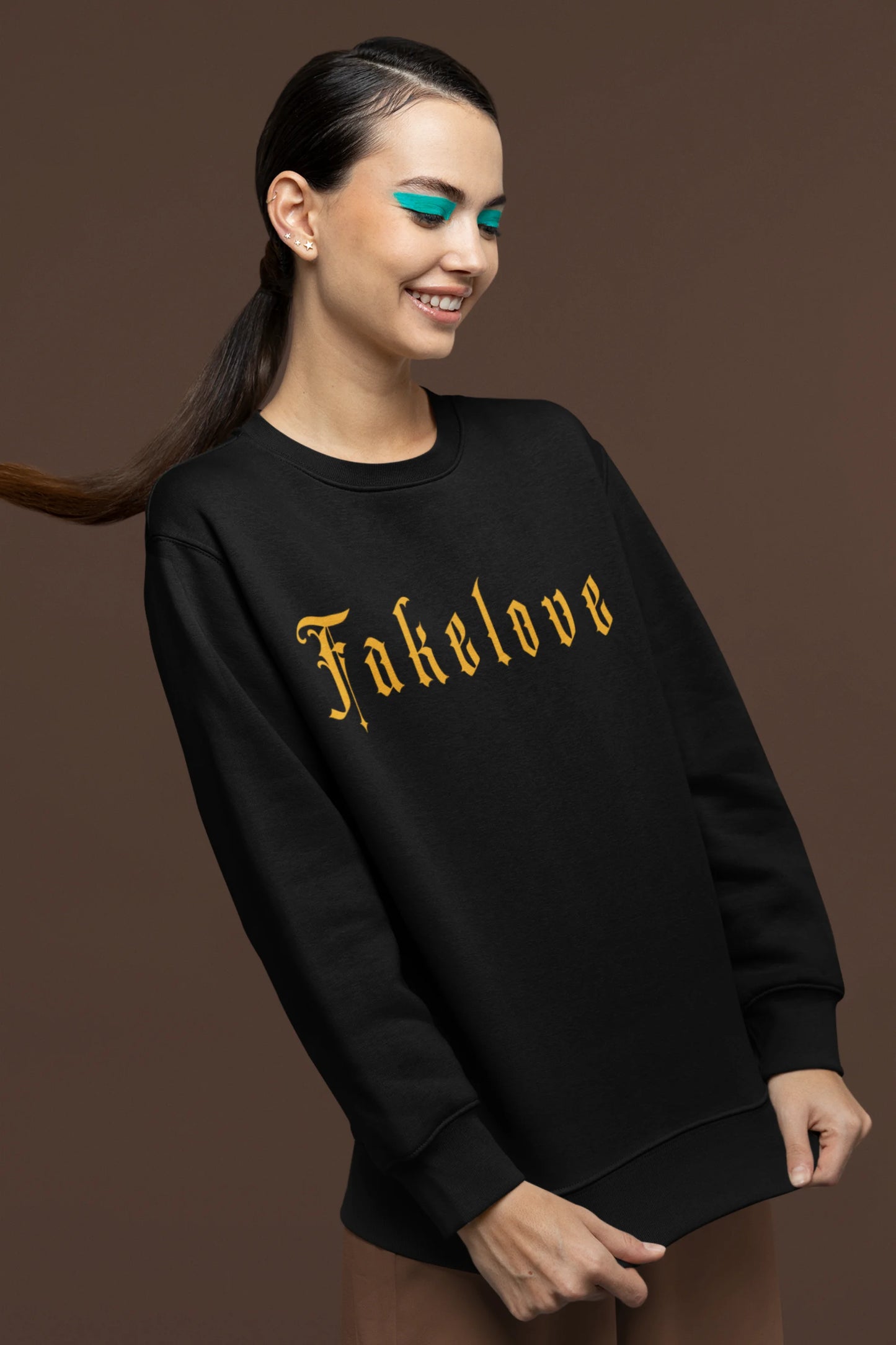 First front view of a female model wearing a black sweatshirt with a brutalist design featuring a fallen angel statue and the phrase "Fake Love".