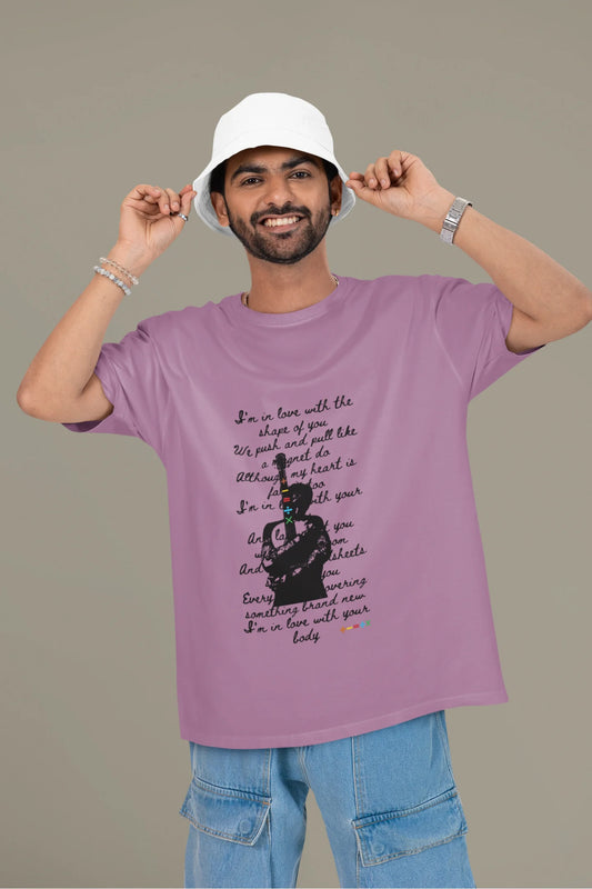 First front view of a male model wearing a dirty purple oversized t-shirt featuring a design inspired by Ed Sheeran's concerts, related to the song "Shape of You."
